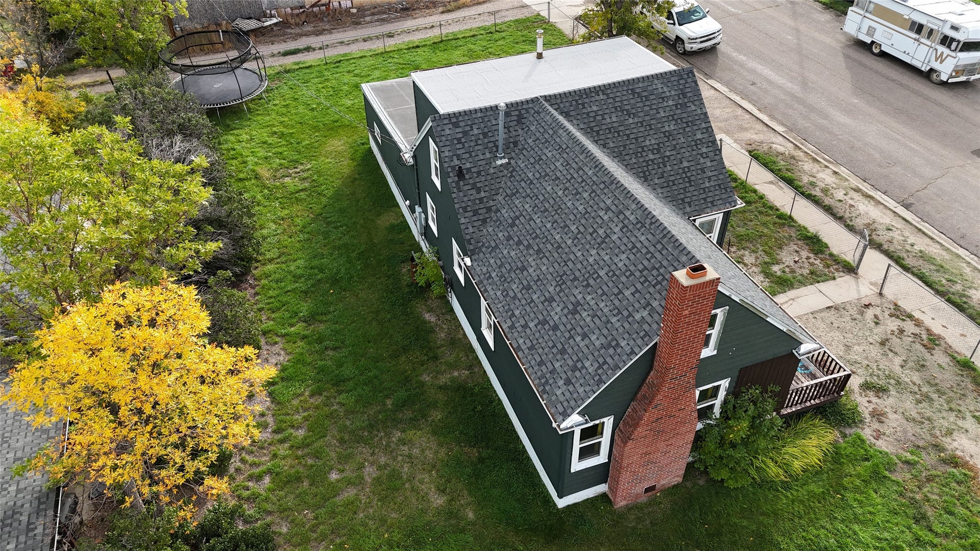 1123 2nd Street N, Shelby, MT 59474 Deep green exterior with white trim, asphalt shingle roof, and a prominent brick chimney