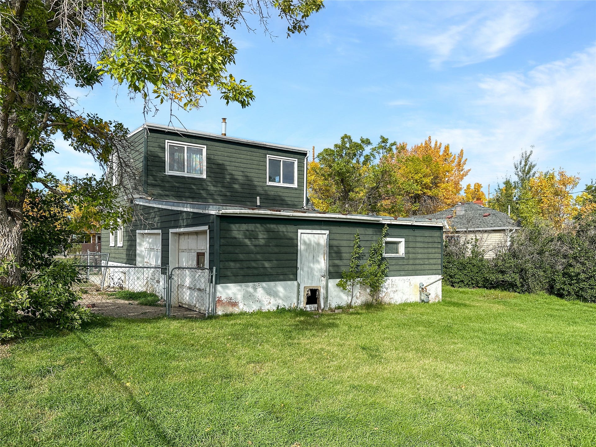 1123 2nd Street N, Shelby, MT 59474 Dark siding with white trim, 2 white garage doors and one white side door. 2 windows upstairs.