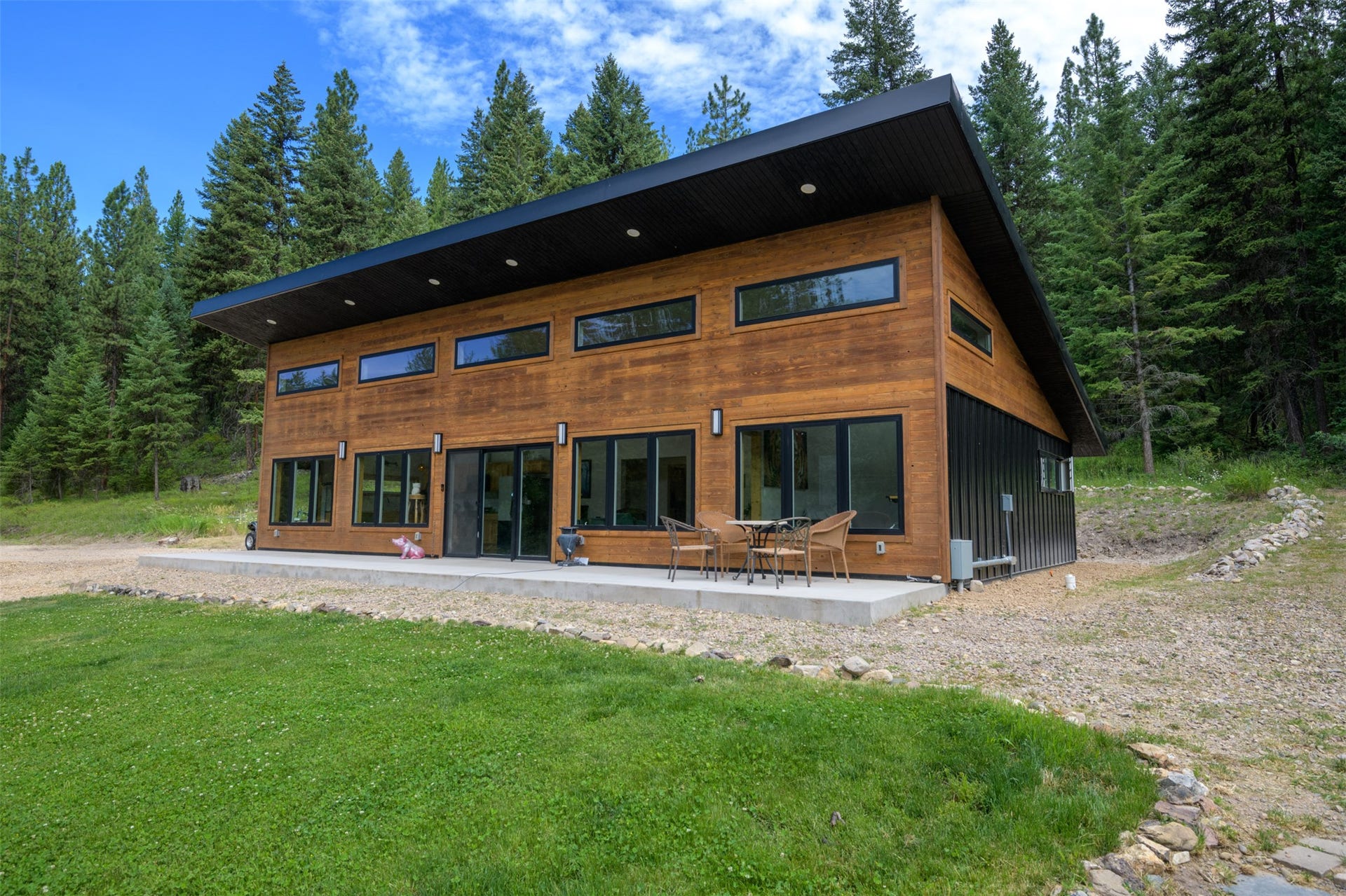 Modern architectural design with wood-finish siding, black metal accents, and an expansive concrete patio