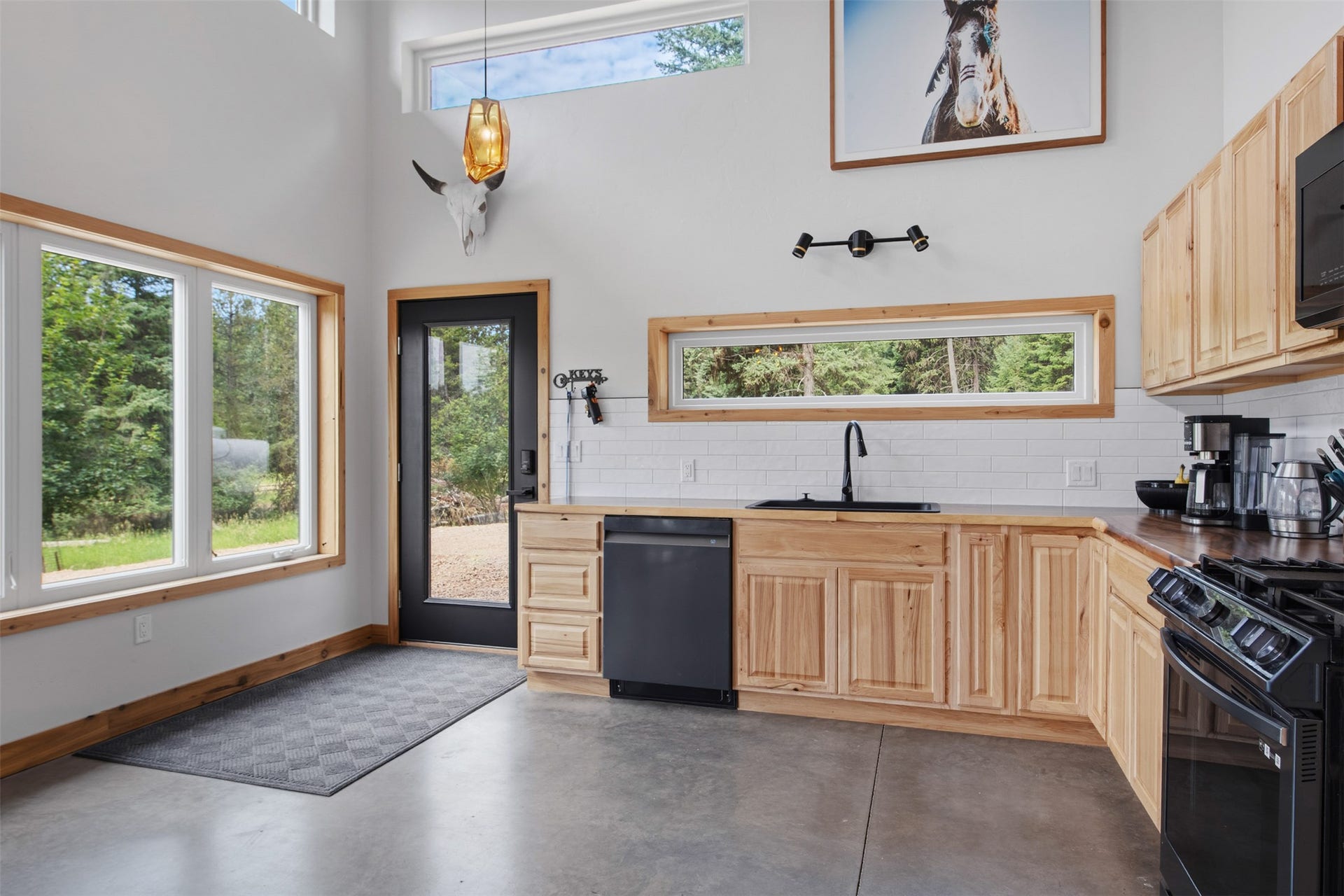 Kitchen featuring natural wood cabinetry, white subway tile backsplash, and a black appliance suite