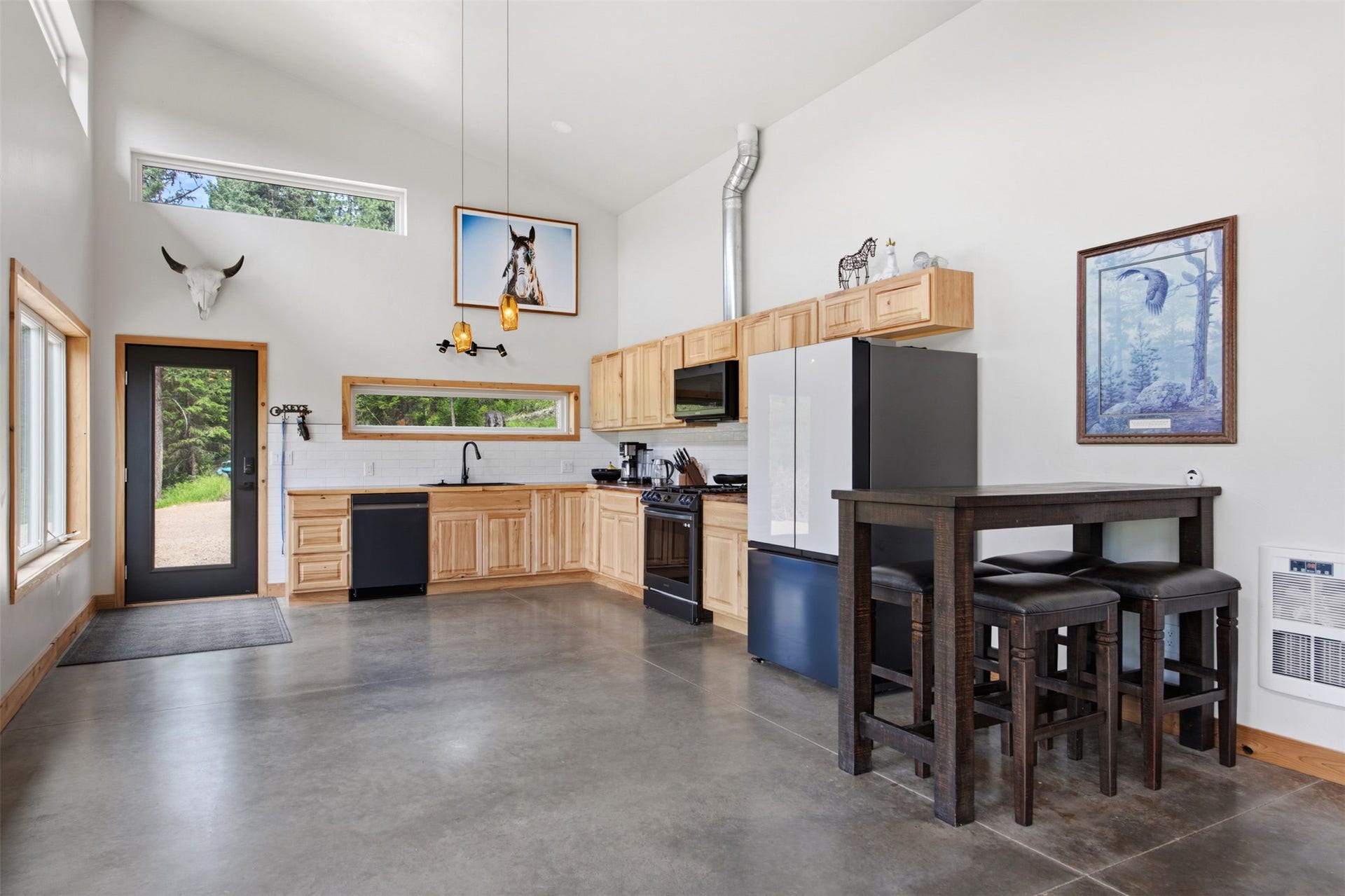 Kitchen featuring light wood cabinetry, black appliances, a white subway tile backsplash, and a polished concrete floor
