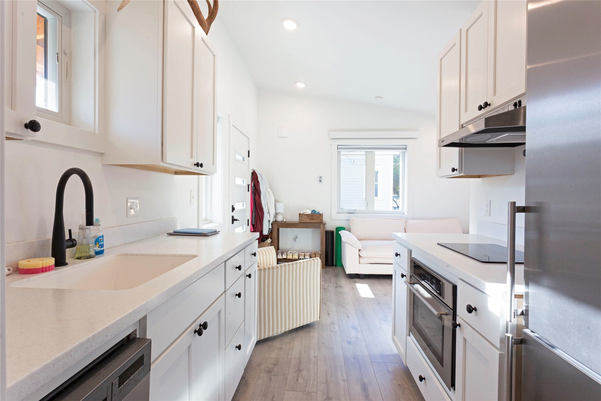 White cabinetry, light countertops, wood-finish flooring, stainless steel appliances, and recessed lighting