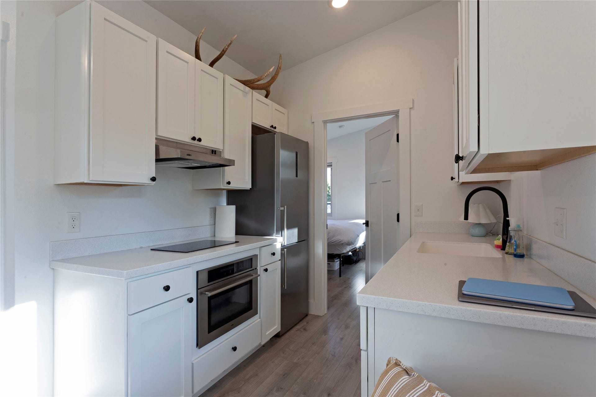 Kitchen featuring white shaker cabinetry, light-toned countertops, stainless steel appliances, and wood-finish flooring
