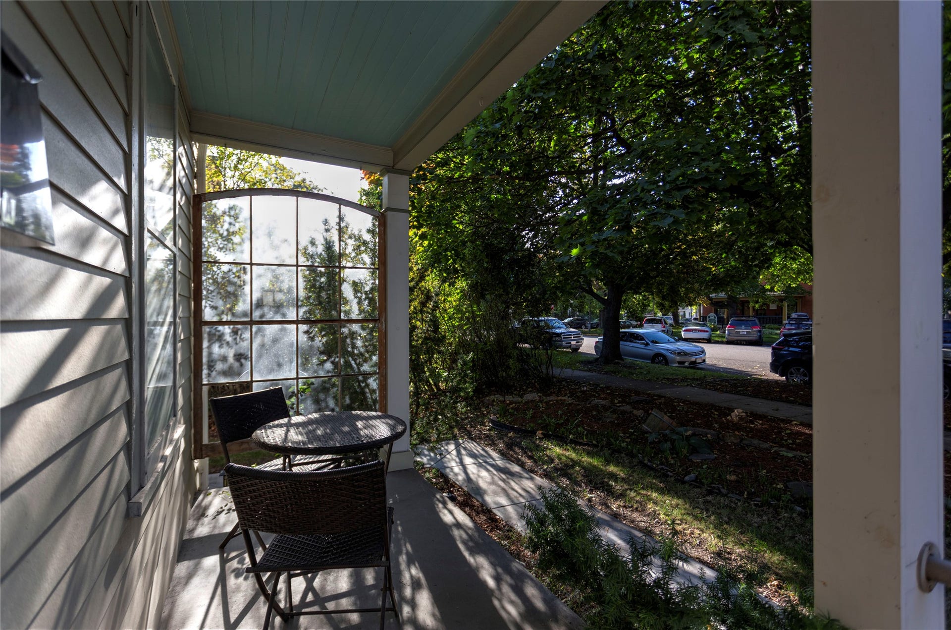Covered porch with siding exterior, arched multi-pane window, and a painted ceiling