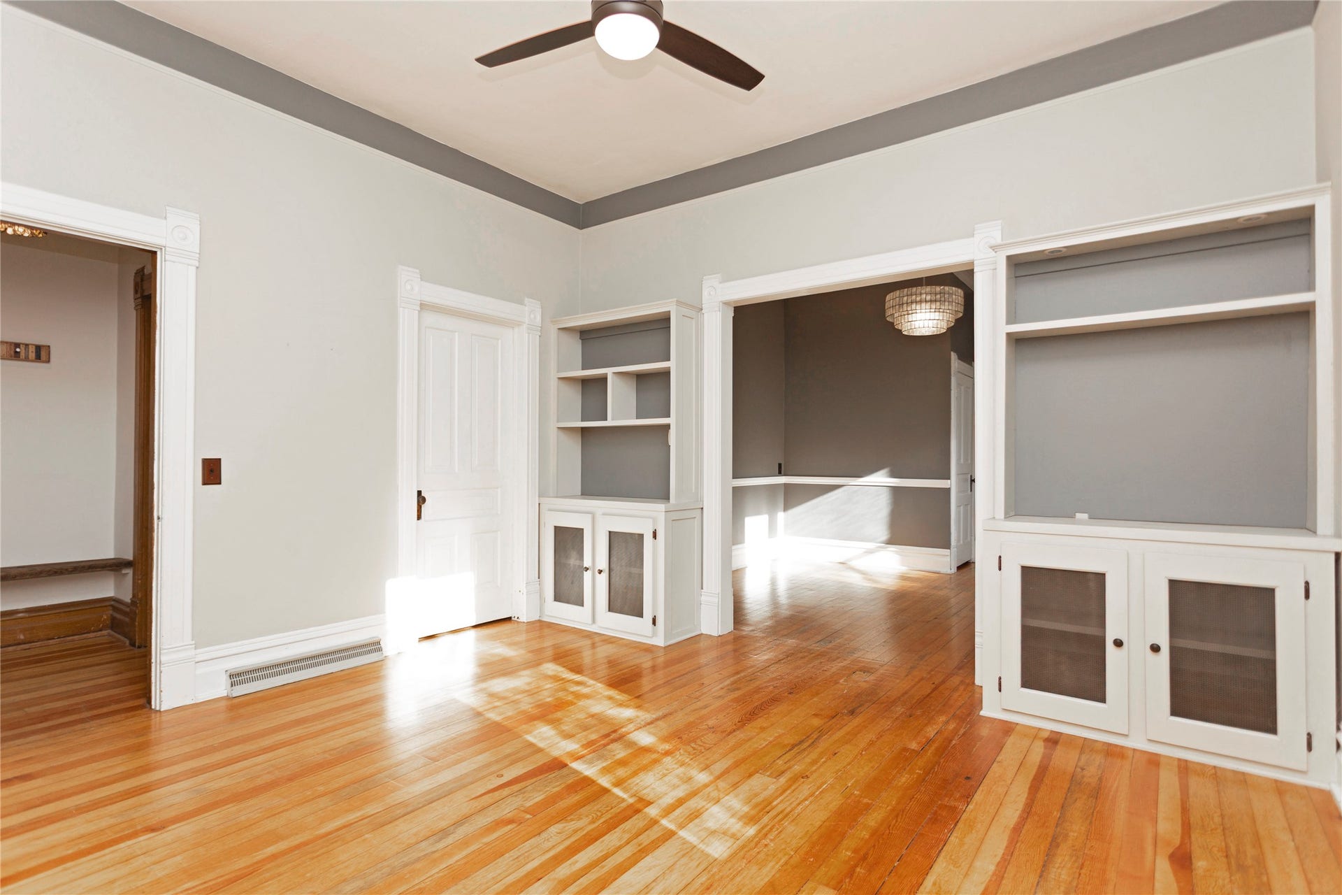 Hardwood flooring, white built-in cabinetry, ceiling fan, wide entryway, and detailed white trim