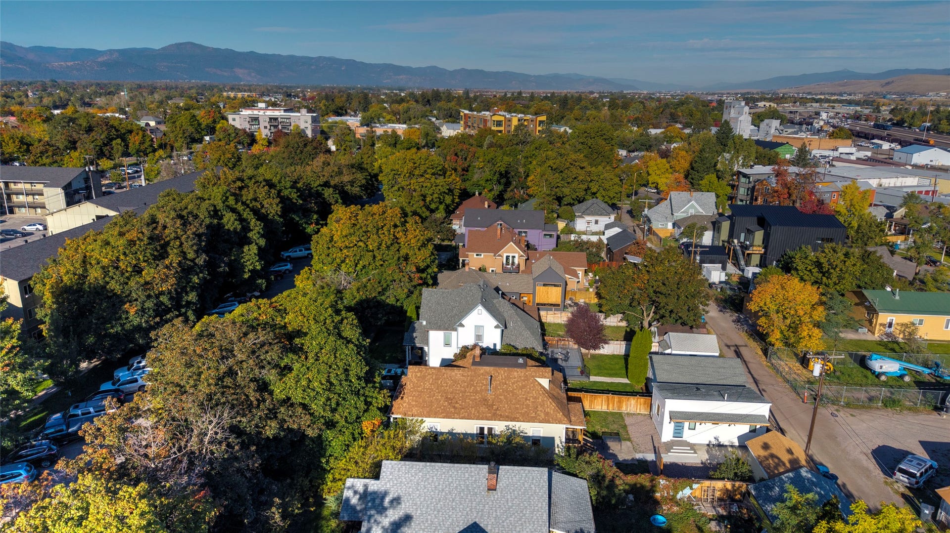 Residential neighborhood with mature trees, established properties, and distant mountain backdrop