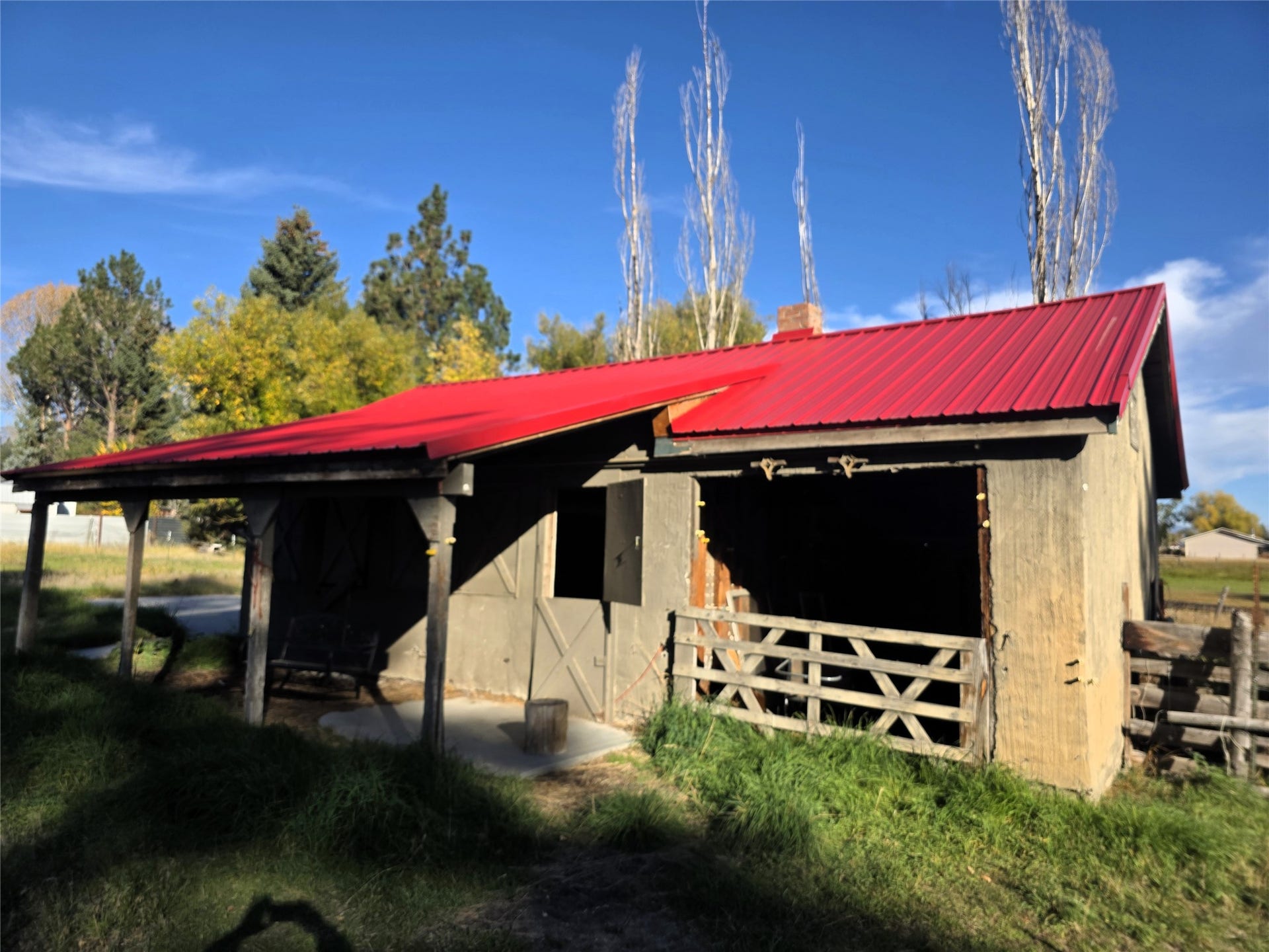 115 Ricketts Road, Hamilton, MT 59840 Red metal roof, wood-sided structure, exposed wood rafter tails, brick chimney, covered porch with wood posts