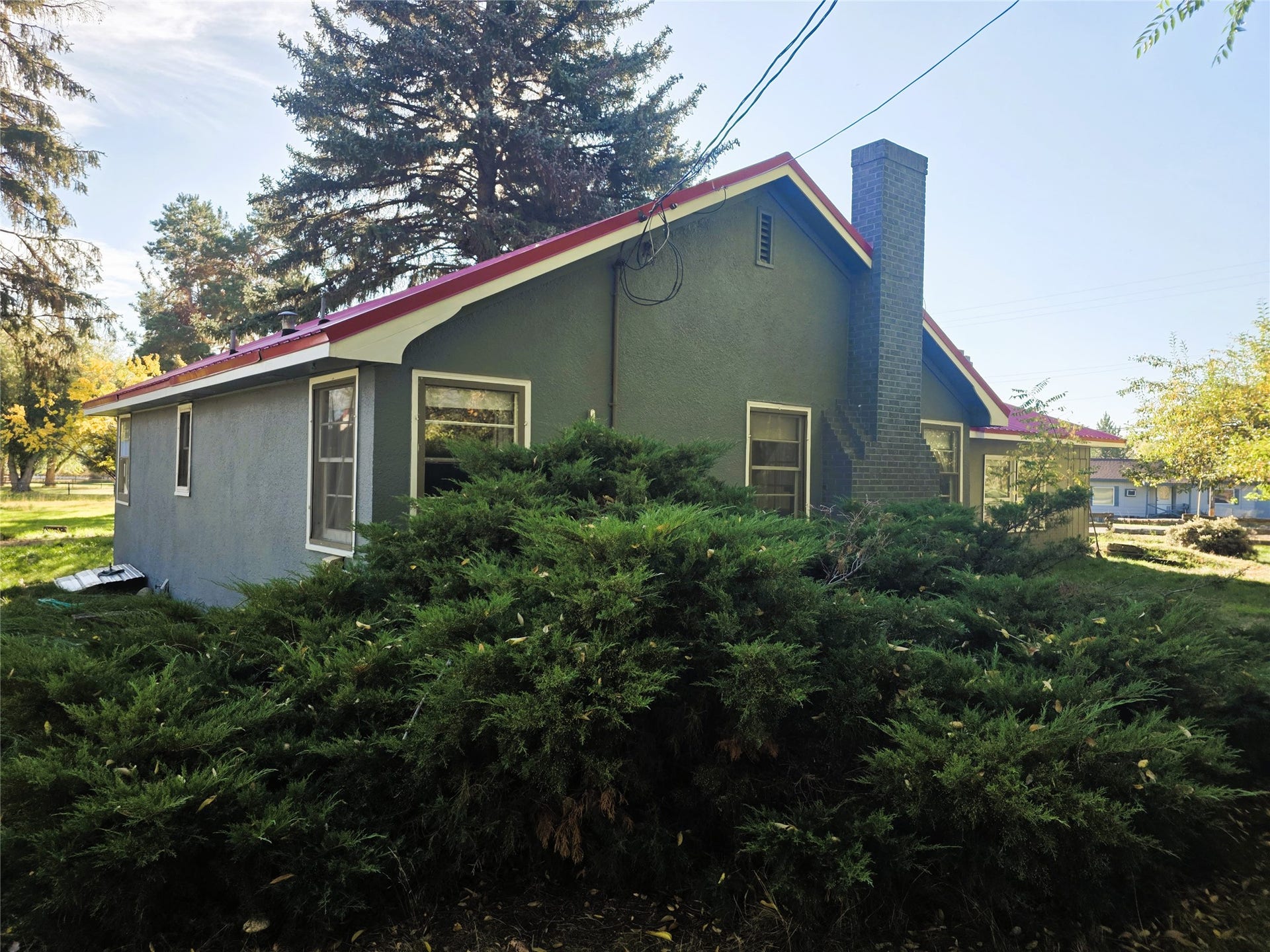 115 Ricketts Road, Hamilton, MT 59840 Exterior featuring a stucco finish, brick chimney, and mature shrubbery