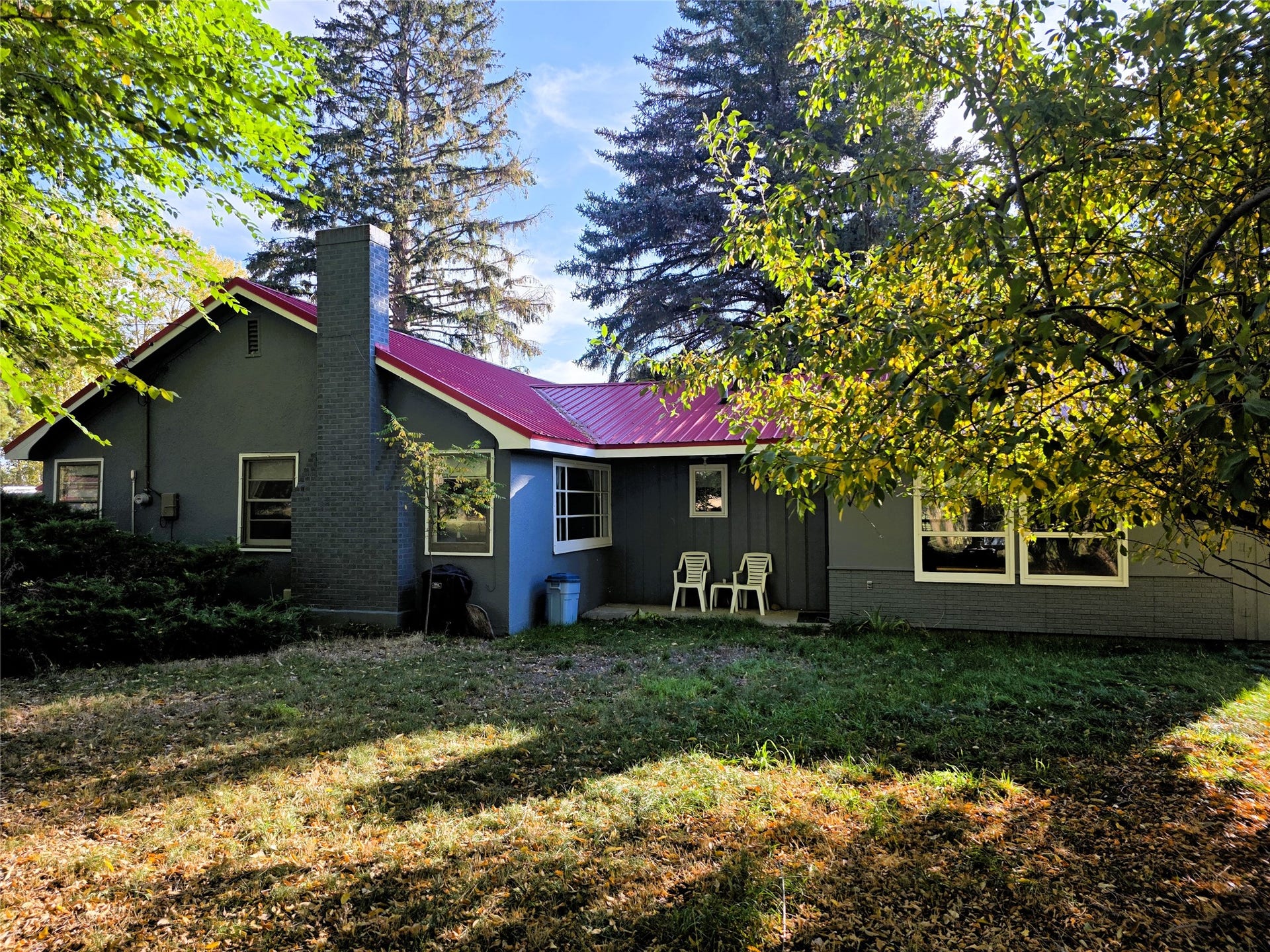 115 Ricketts Road, Hamilton, MT 59840 Exterior featuring a red metal roof, brick chimney, and multiple windows
