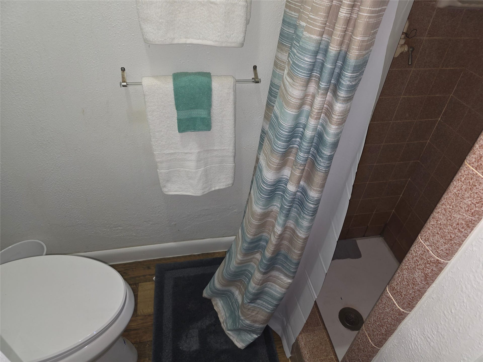 115 Ricketts Road, Hamilton, MT 59840 White toilet fixture, textured white walls, and a tiled shower enclosure in guest house