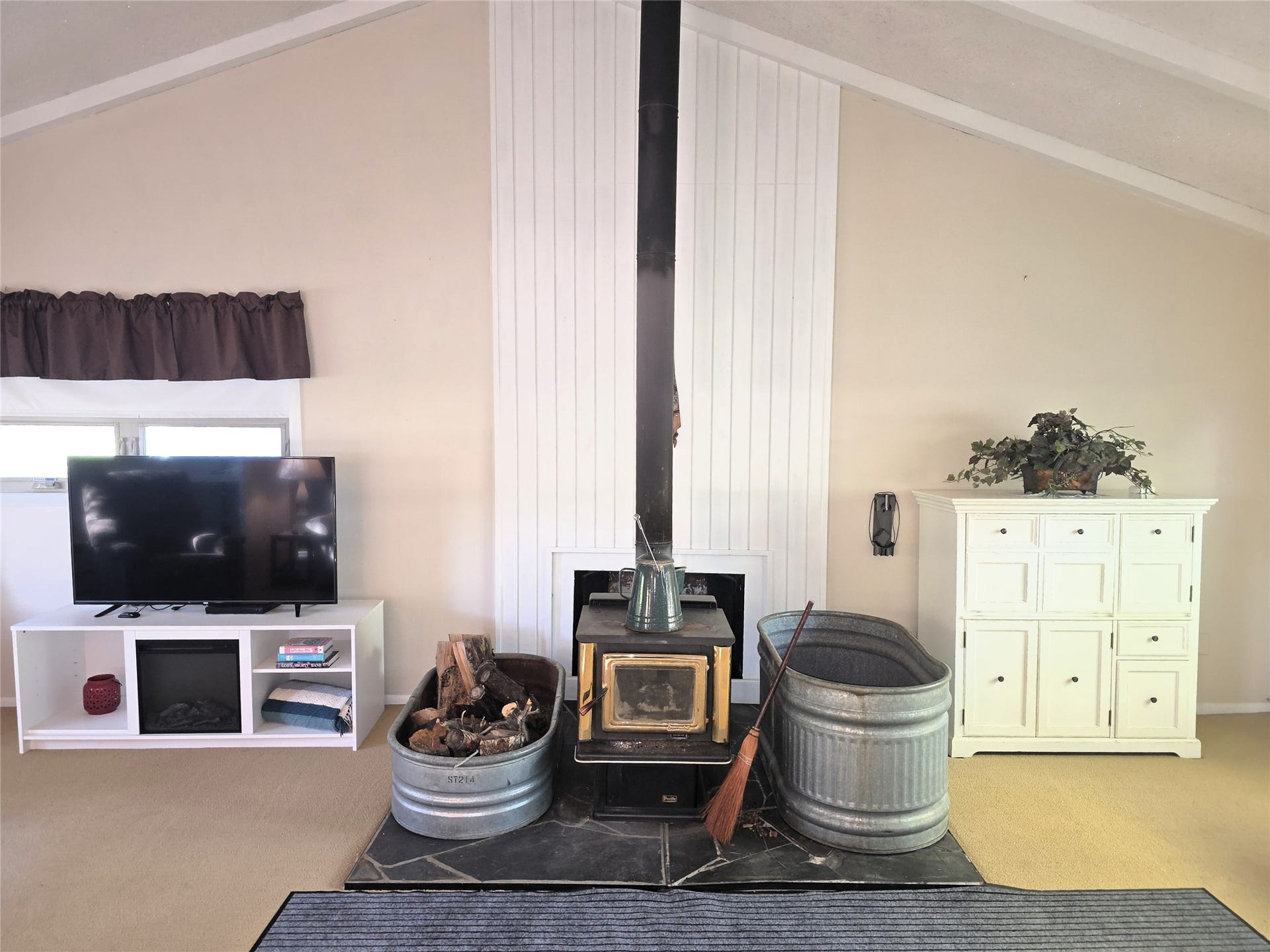 115 Ricketts Road, Hamilton, MT 59840 Vaulted ceiling with exposed beams, wood-burning stove, slate hearth, and white shiplap accent wall
