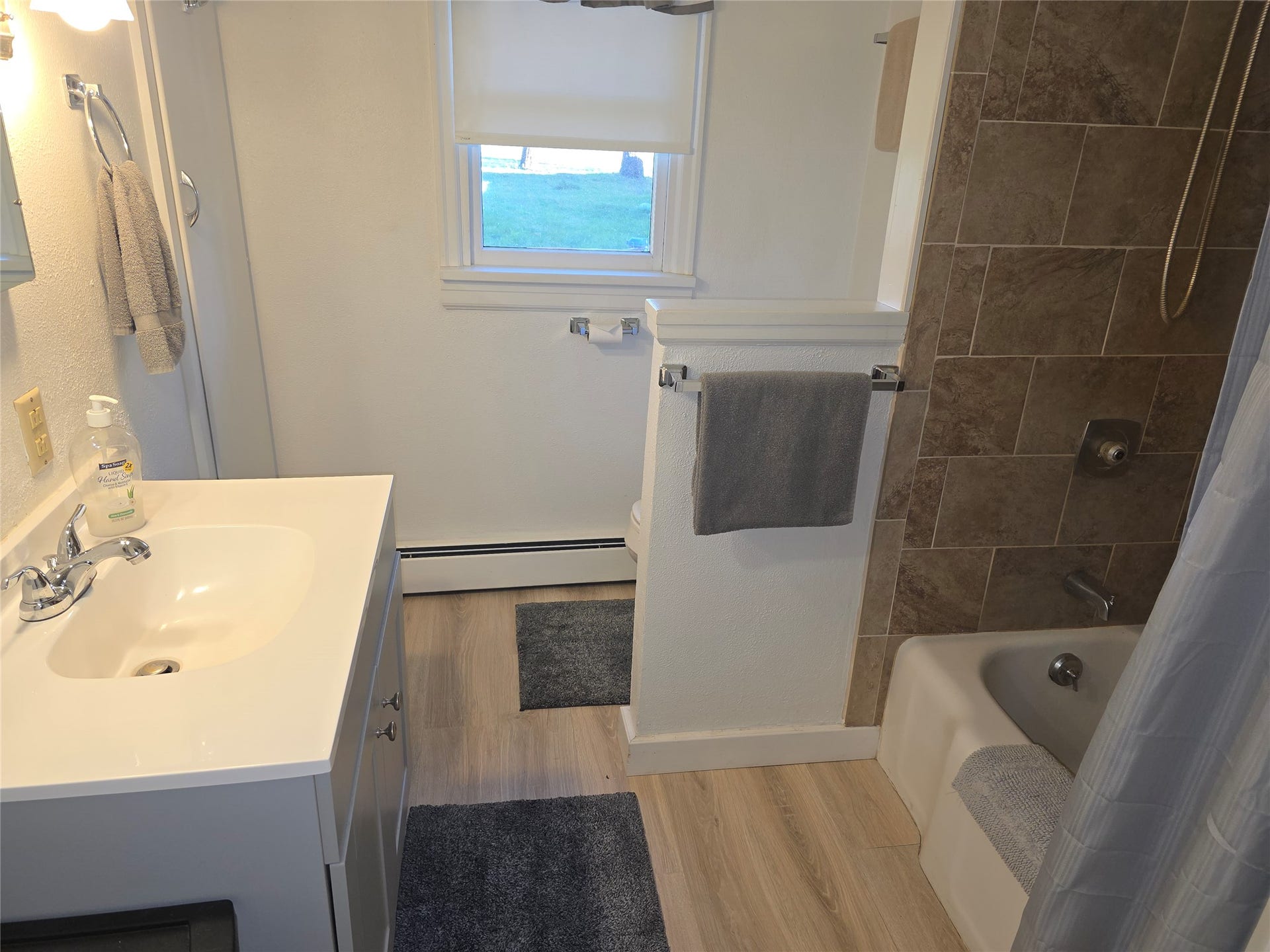 115 Ricketts Road, Hamilton, MT 59840 Bathroom featuring a light wood-finish floor, white vanity with integrated sink, shower-over-tub combination, and tiled shower surround