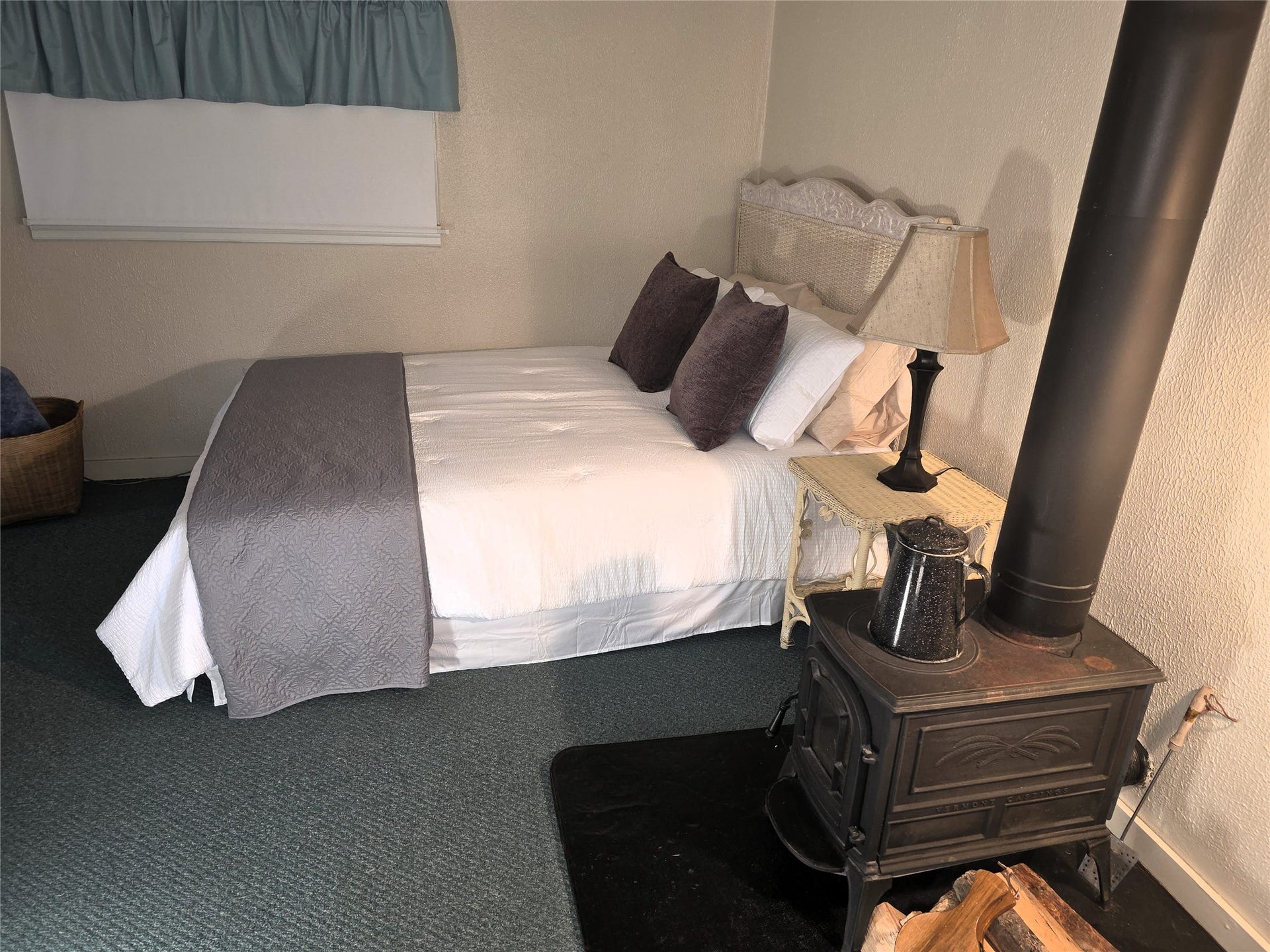 115 Ricketts Road, Hamilton, MT 59840 Cast iron wood-burning stove with a protective hearth, light-toned wall finish, and wall-to-wall carpeting in guest house