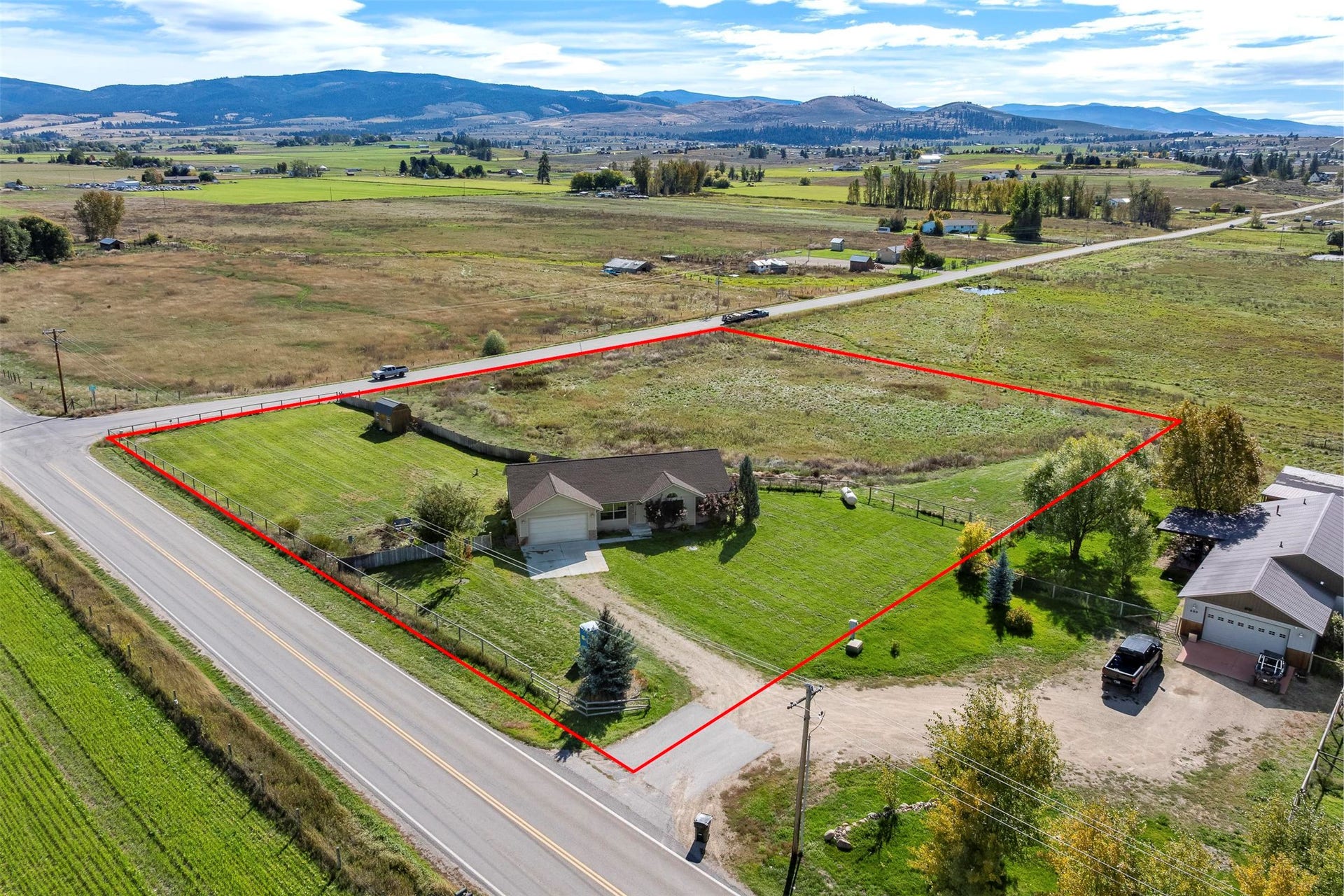 Ranch-style residence featuring an attached two-car garage, expansive lawn, and mature trees