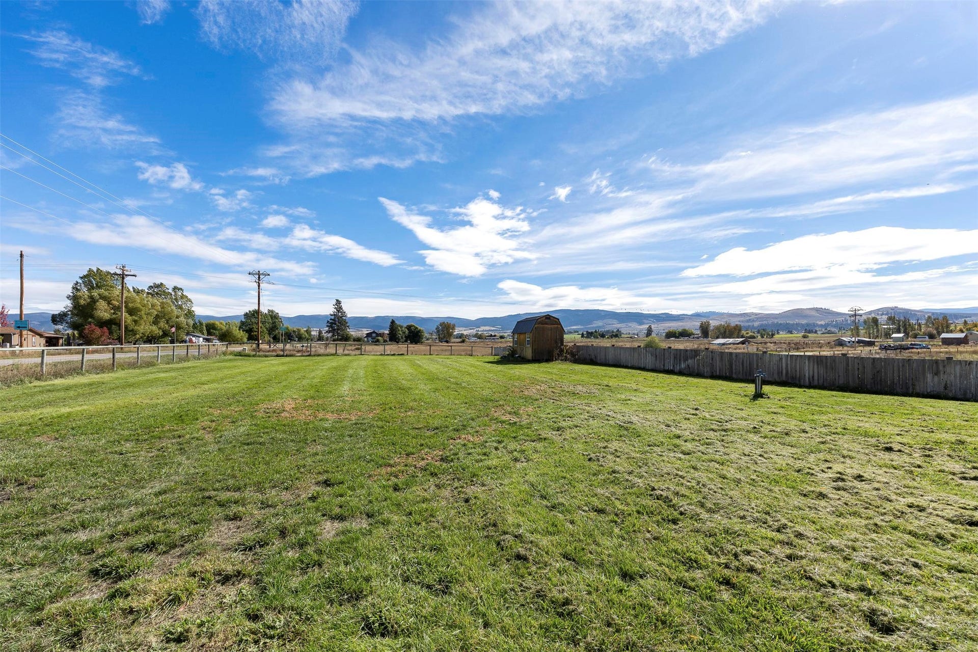 Expansive green lawn with a wood-plank fence border and distant mountainous terrain