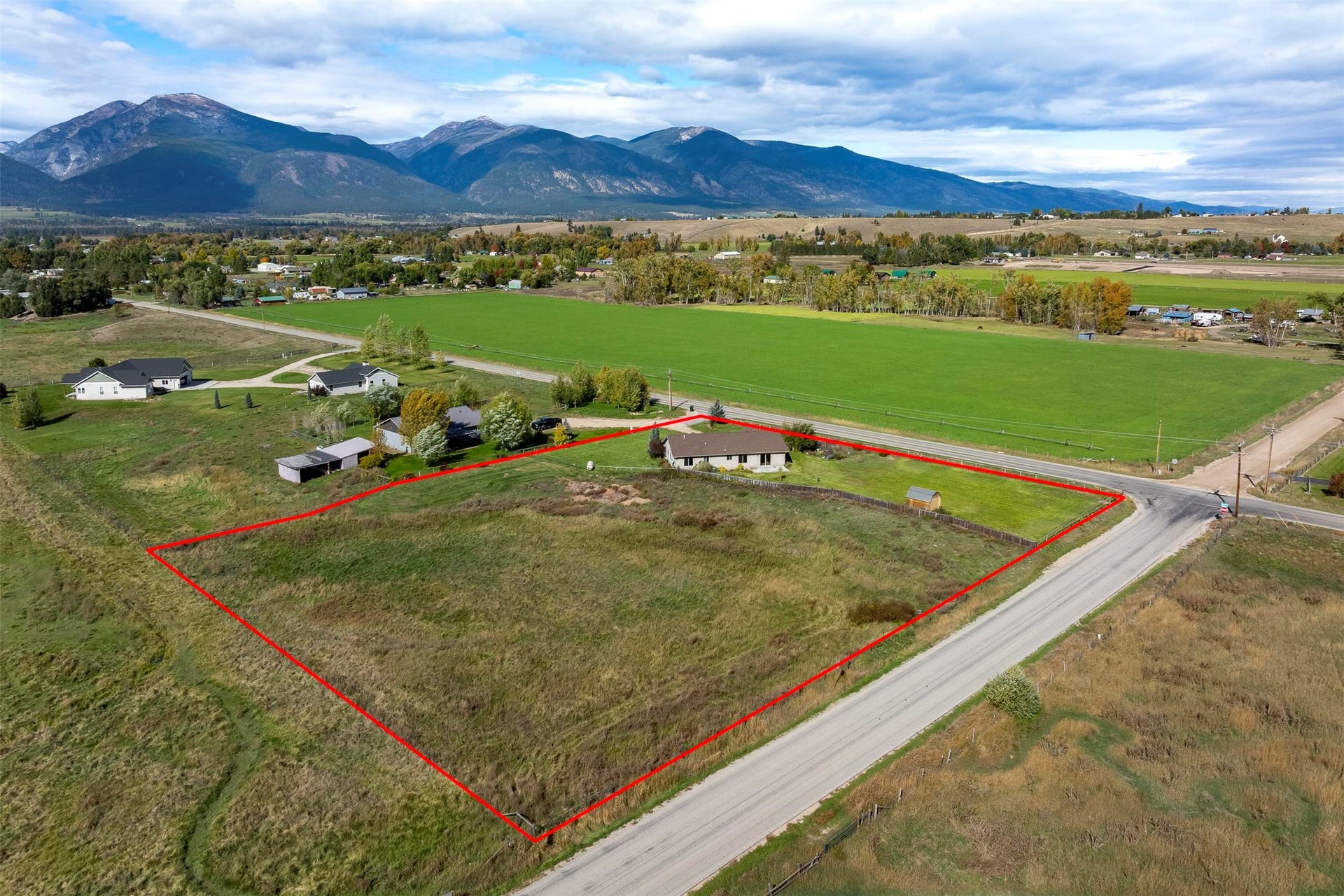 Expansive property featuring a single-story residence, multiple outbuildings, and a large open field