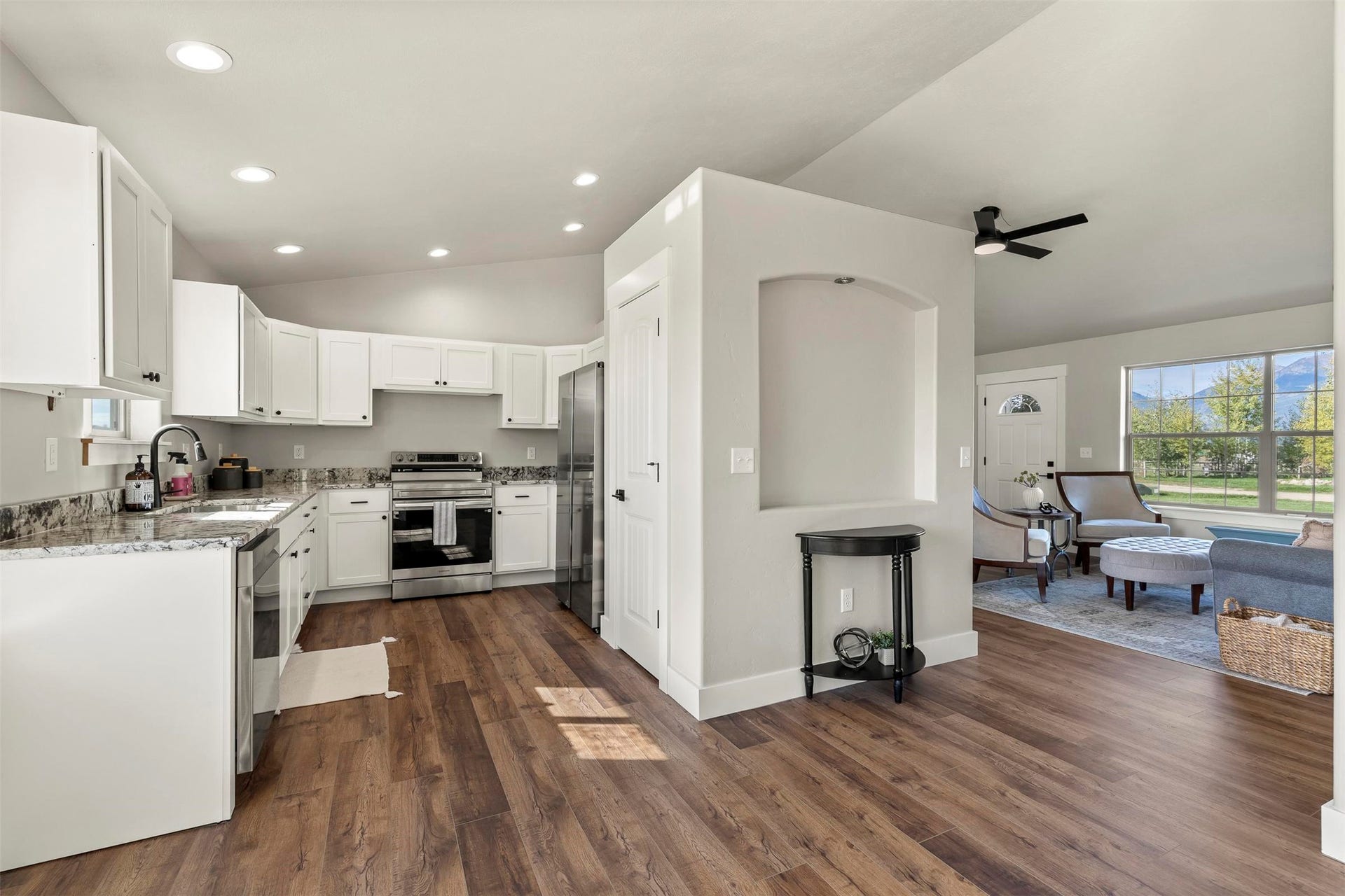 Kitchen featuring white cabinetry, stainless steel appliances, speckled countertops, and wood-finish flooring