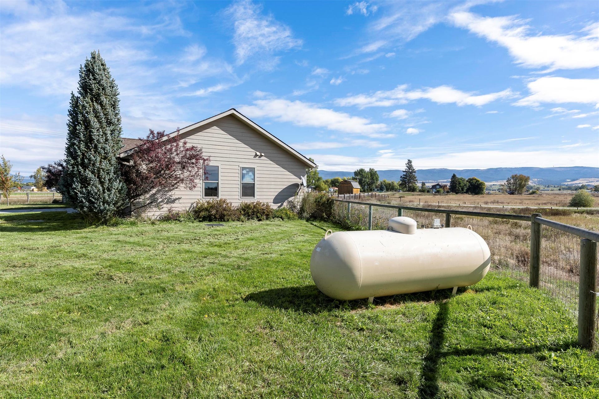 Expansive grassy yard with a wire fence and distant landscape