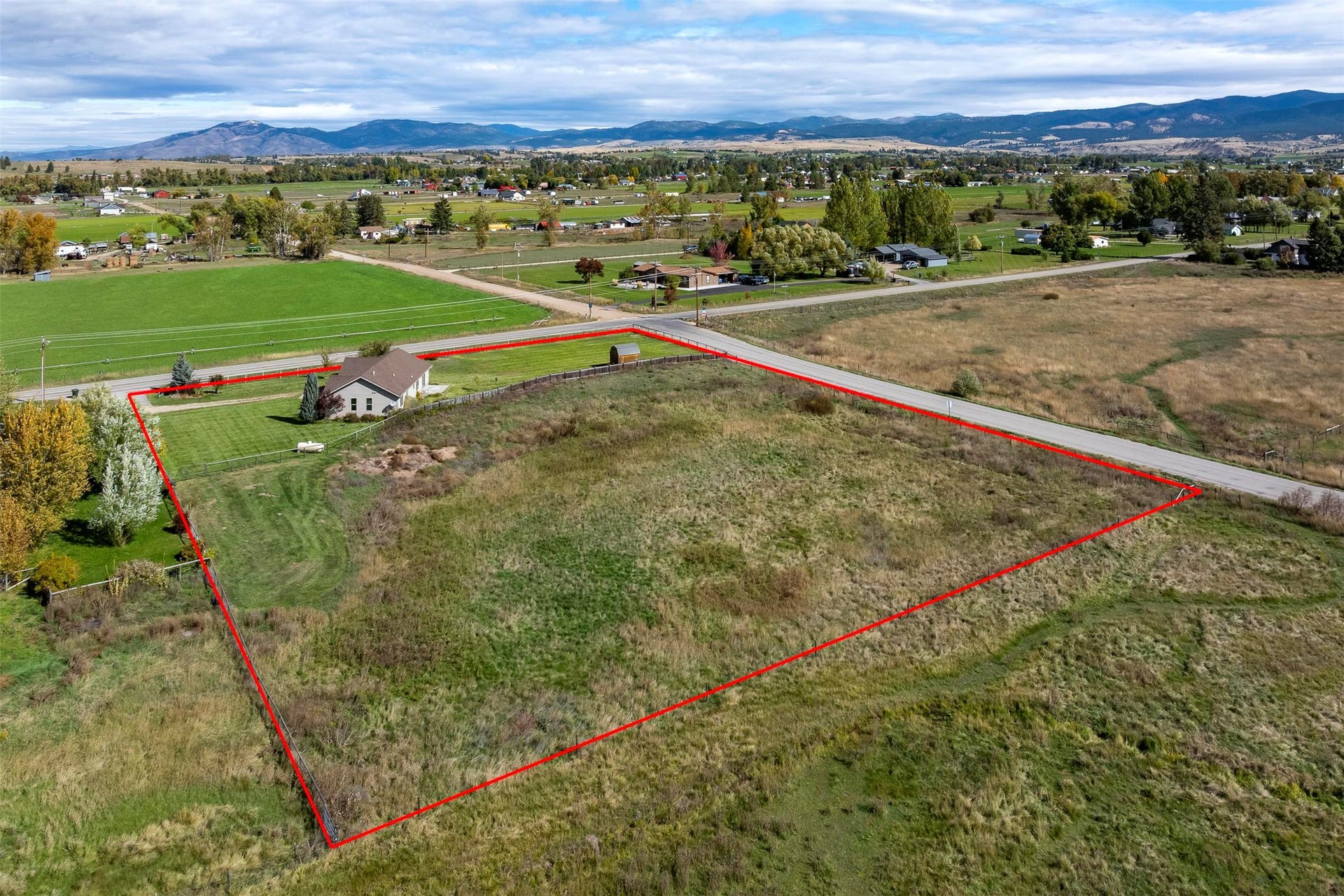 Expansive rural property featuring a single-story residence, a broad expanse of open land, and surrounding natural scenery