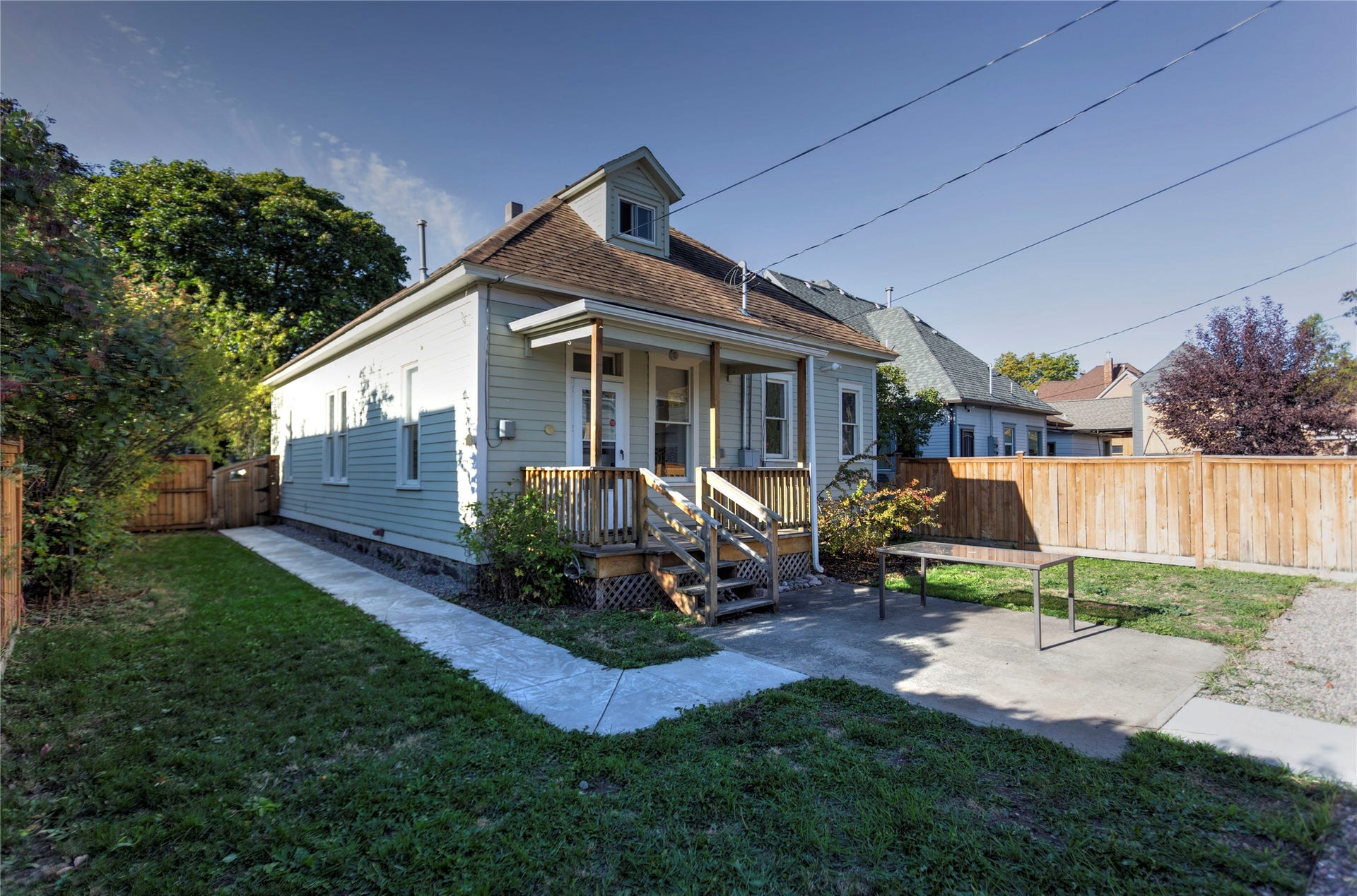 Charming cottage-style residence featuring a classic blue exterior with white trim, front-facing gable with dormer window, and a welcoming covered porch with wooden railings