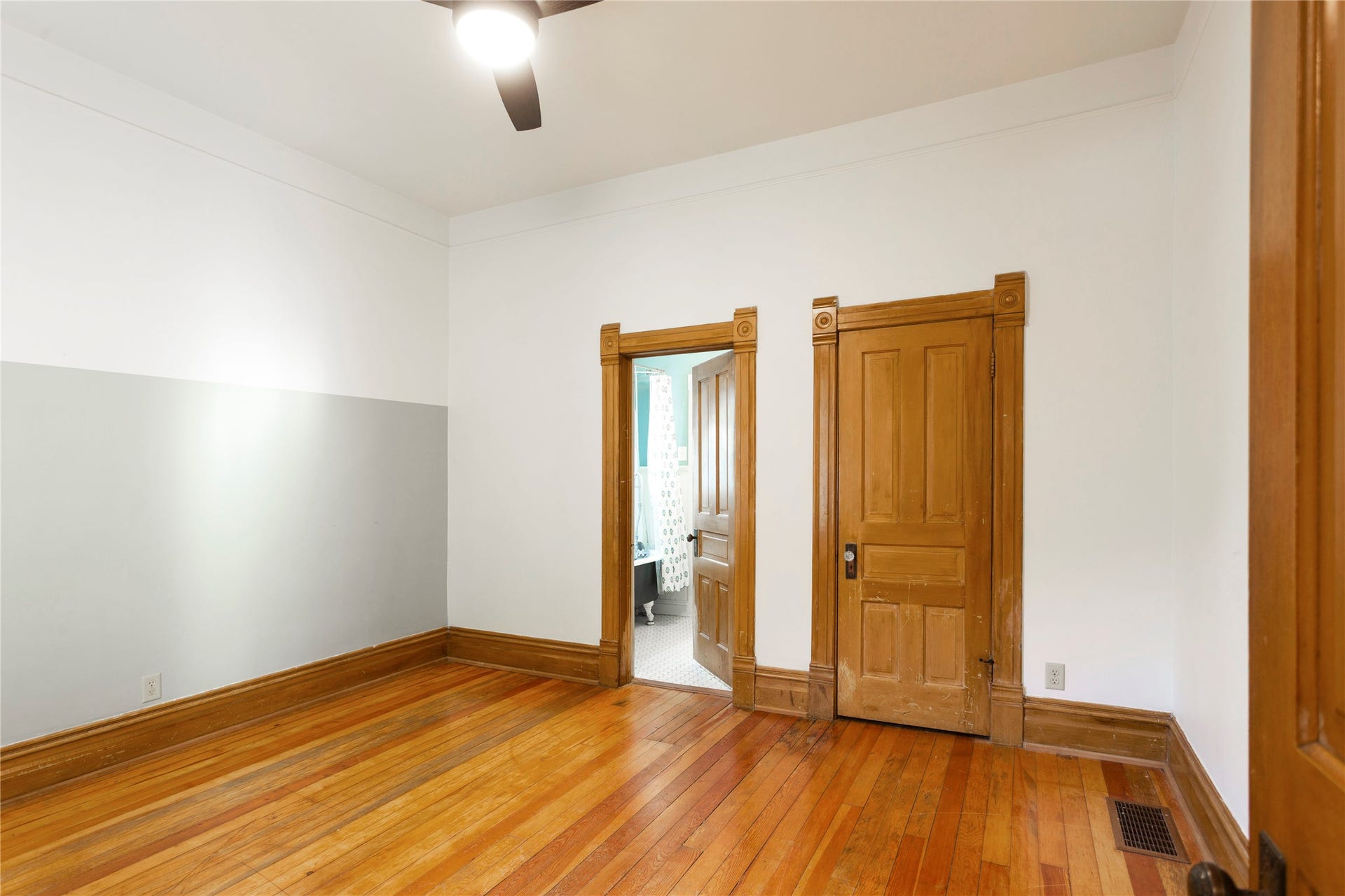 Hardwood flooring, wood-finish doors, detailed wood trim, and a ceiling fan