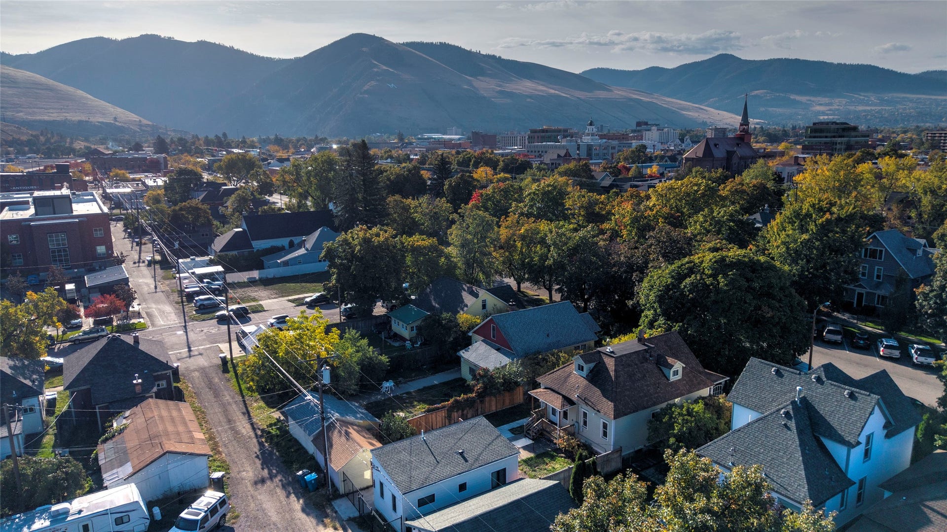 Residential properties with pitched roofs, mature trees, and mountainous terrain