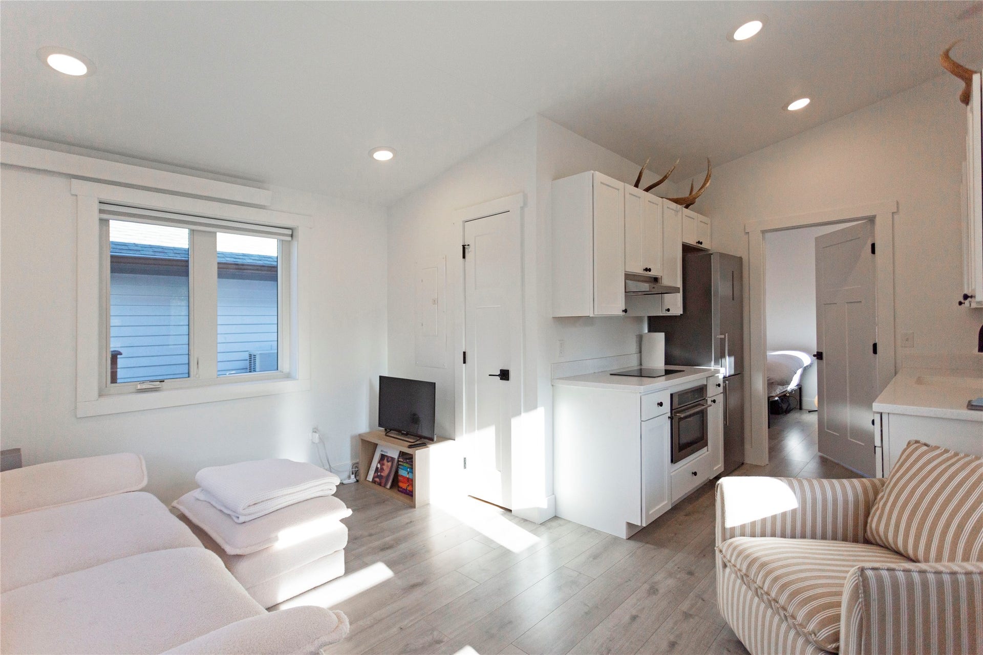 Vaulted ceiling, recessed lighting, wood-finish flooring, white cabinetry, and stainless steel appliances