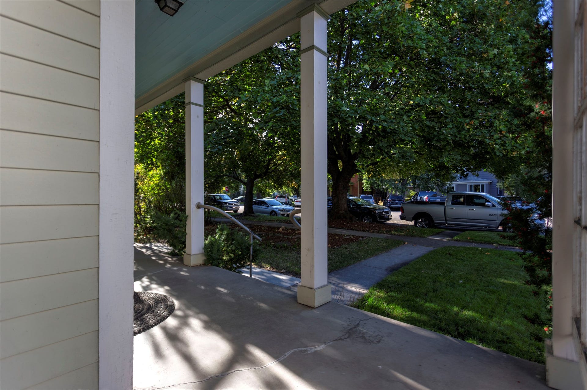Front porch featuring a concrete surface, white support columns, and a blue porch ceiling