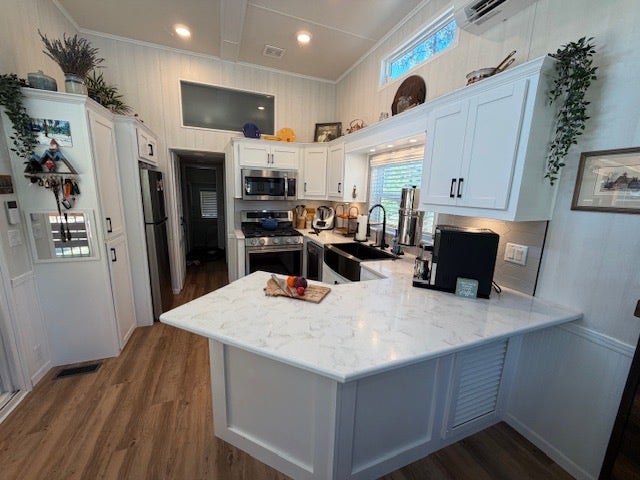 713 Shyrock Loop Dr., Superior, MT 59872 Kitchen featuring white cabinetry with dark hardware, a single basin sink with a black faucet, stainless steel appliances, and light-toned wood-finish flooring