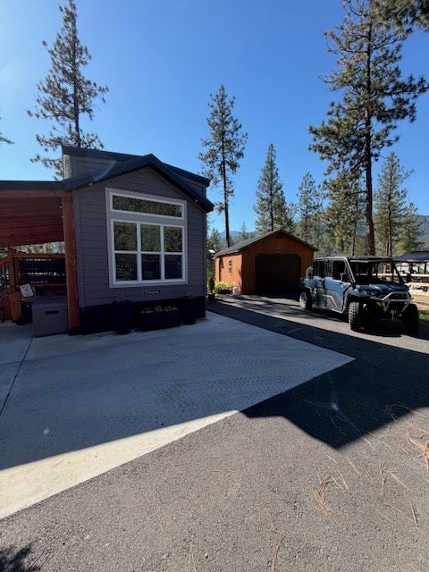 713 Shyrock Loop Dr., Superior, MT 59872 Siding exterior with multiple window panes, an attached awning structure, and a secondary building with a garage door