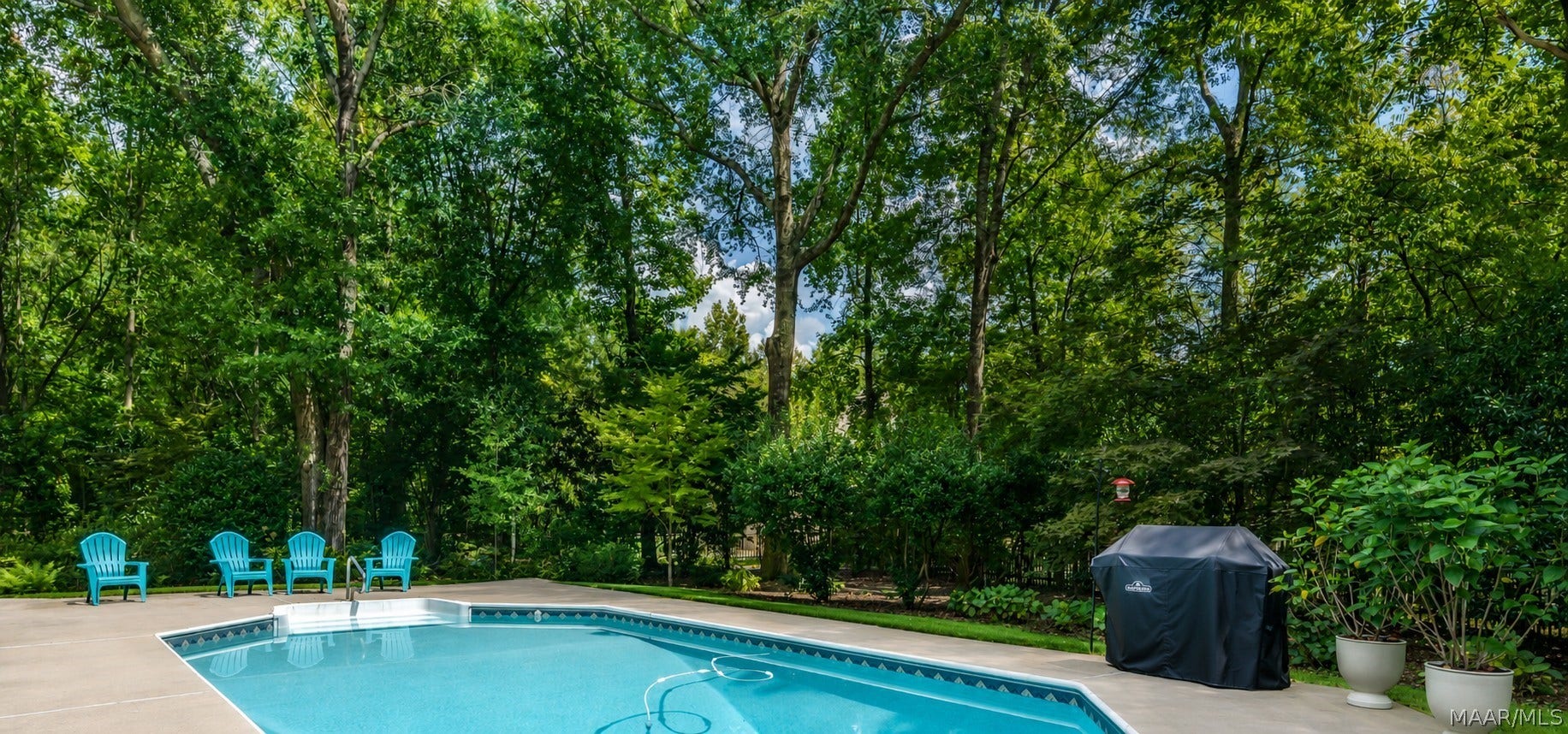 Sparkling in-ground pool surrounded by mature trees and lush landscaping, creating a wonderfully private backyard retreat.