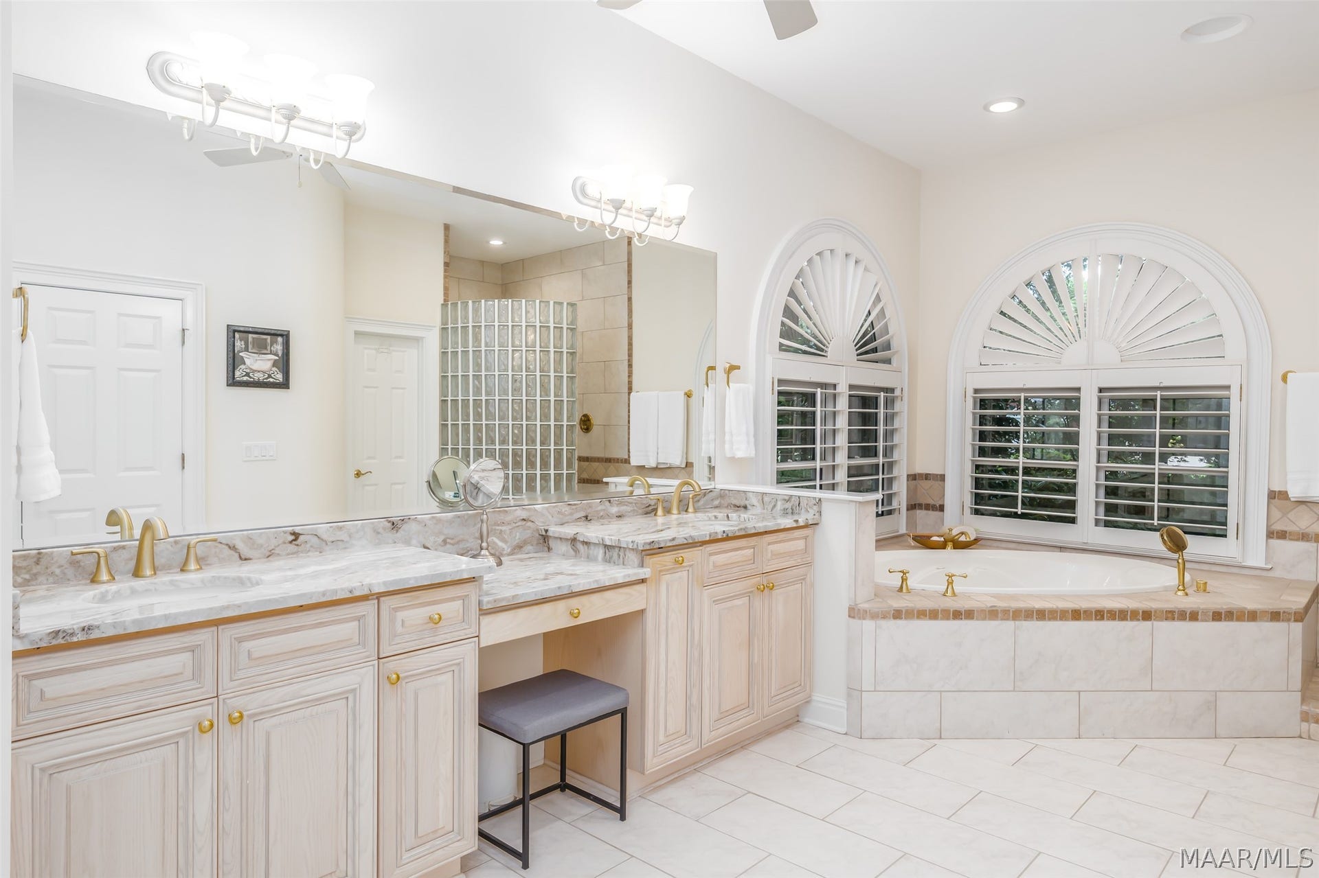 Roomy owners bath with dual vanities, dedicated makeup area, soaking tub and distinctive arched windows.