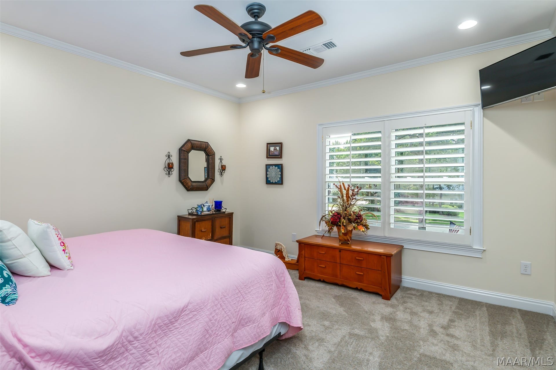 Spacious secondary bedroom with abundant natural light, plantation shutters, crown molding and plenty of room for additional furnishings.