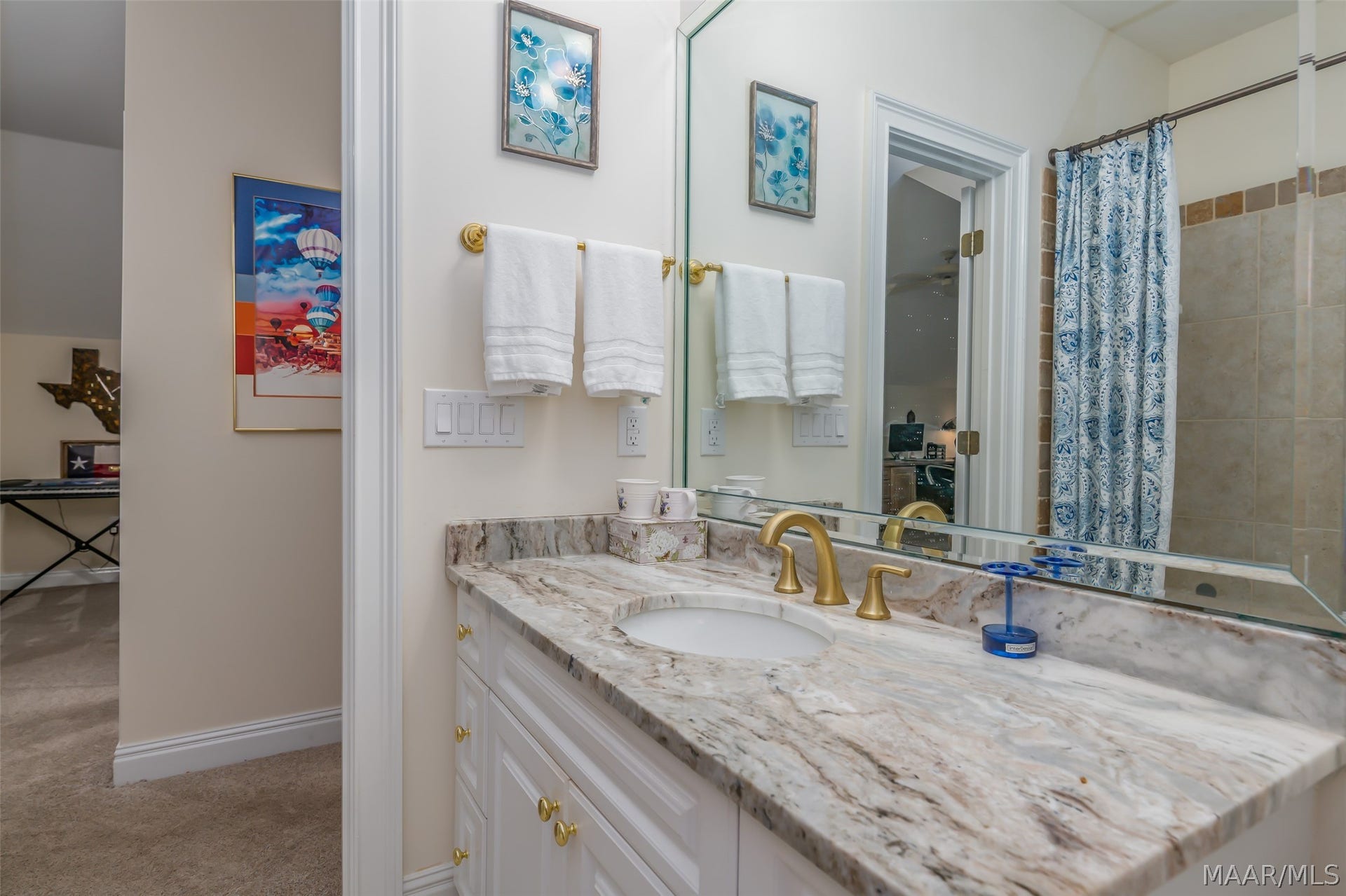 Attractive full bath with stone-topped vanity, tiled shower and warm brass accents.