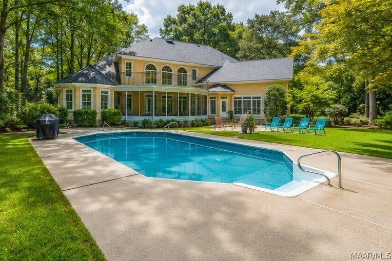 Backyard retreat featuring an in-ground pool, expansive lawn, mature landscaping and a spacious screened porch overlooking it all.