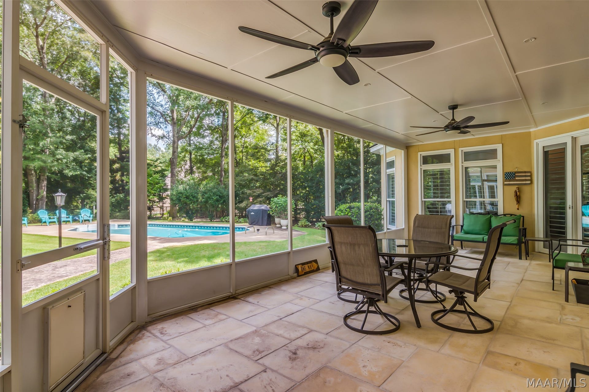 Roomy screened porch offers exceptional outdoor living and dining space with ceiling fans and beautiful views of the pool and backyard.