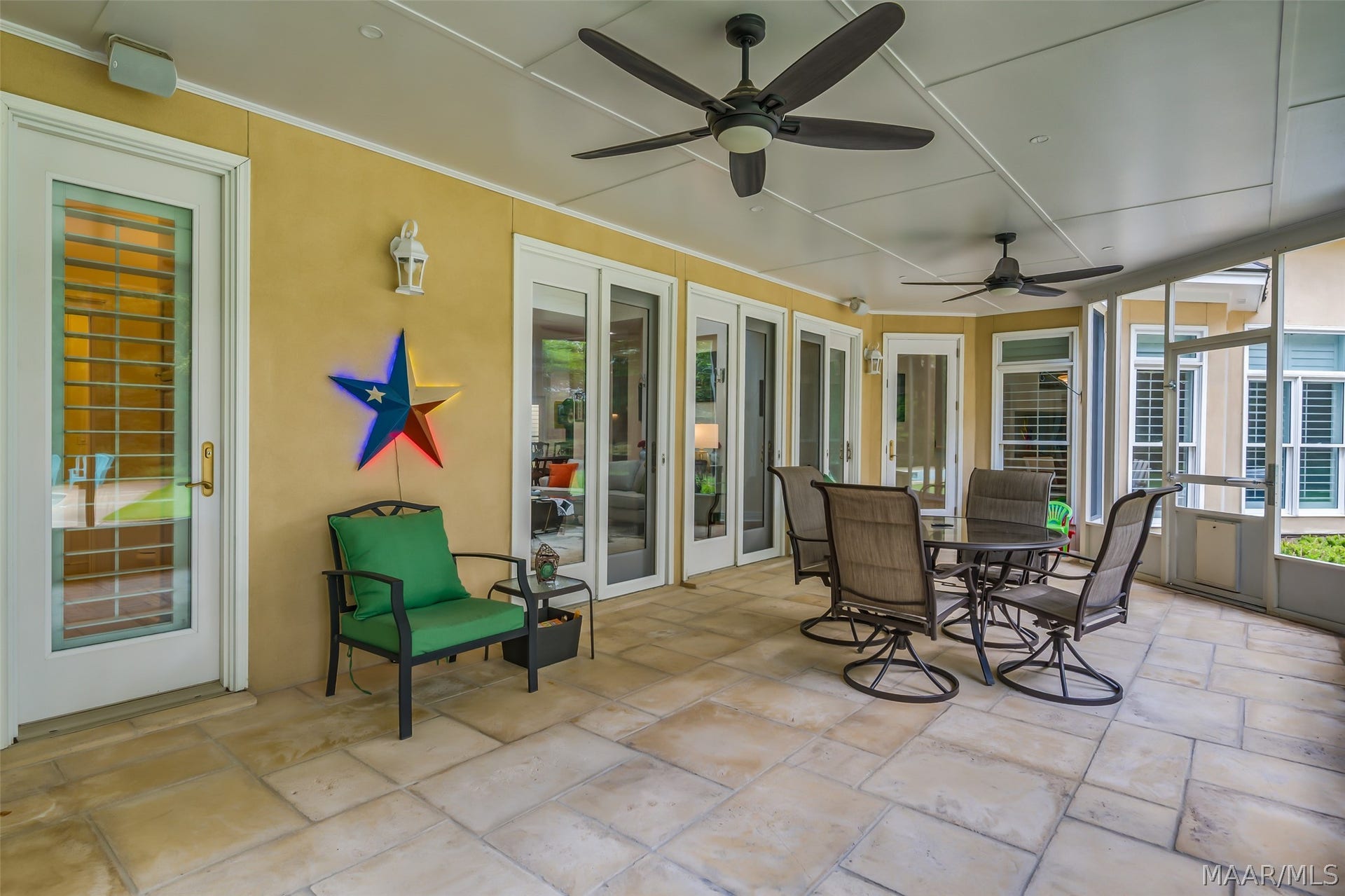 Tiled screened porch extends the home's living space outdoors with multiple seating areas, ceiling fans and plenty of room for dining and entertaining.
