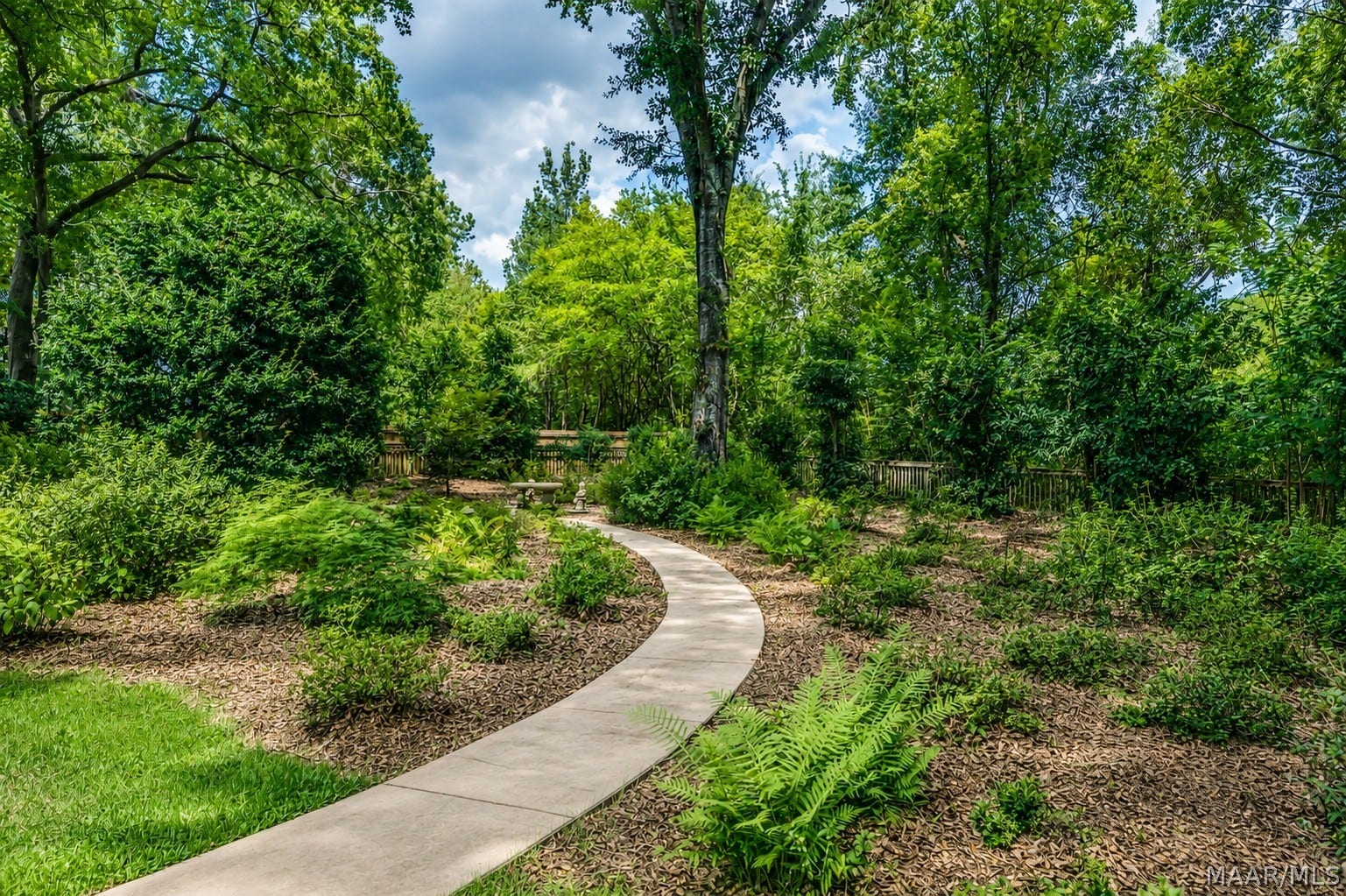 Meandering garden path winds through a beautifully wooded landscape filled with mature trees, ferns and established plantings.