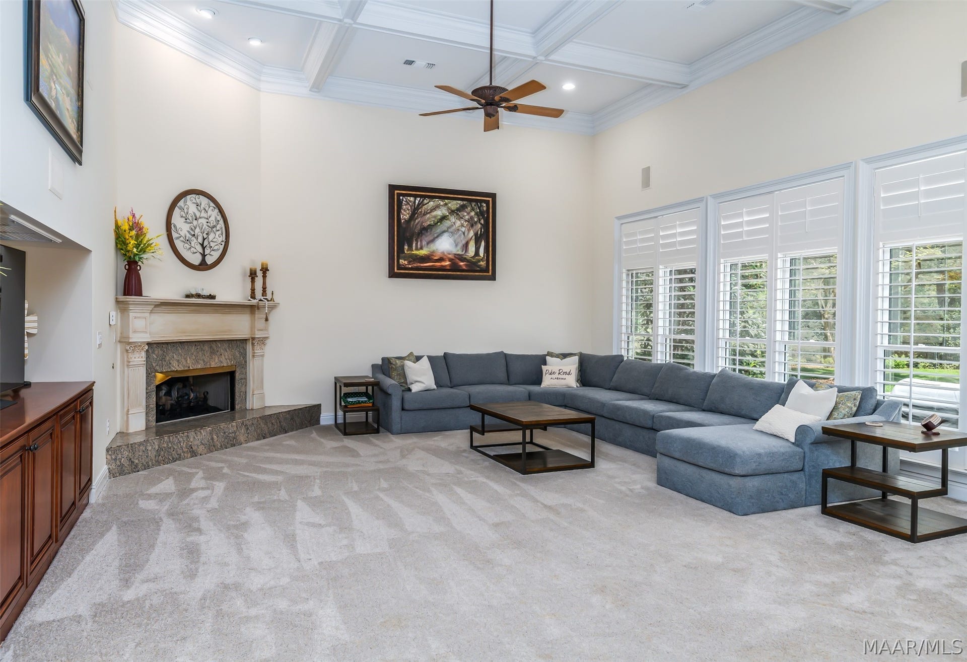 Spacious and inviting family room featuring a fireplace, coffered ceiling, built-ins and a wall of windows overlooking the backyard.