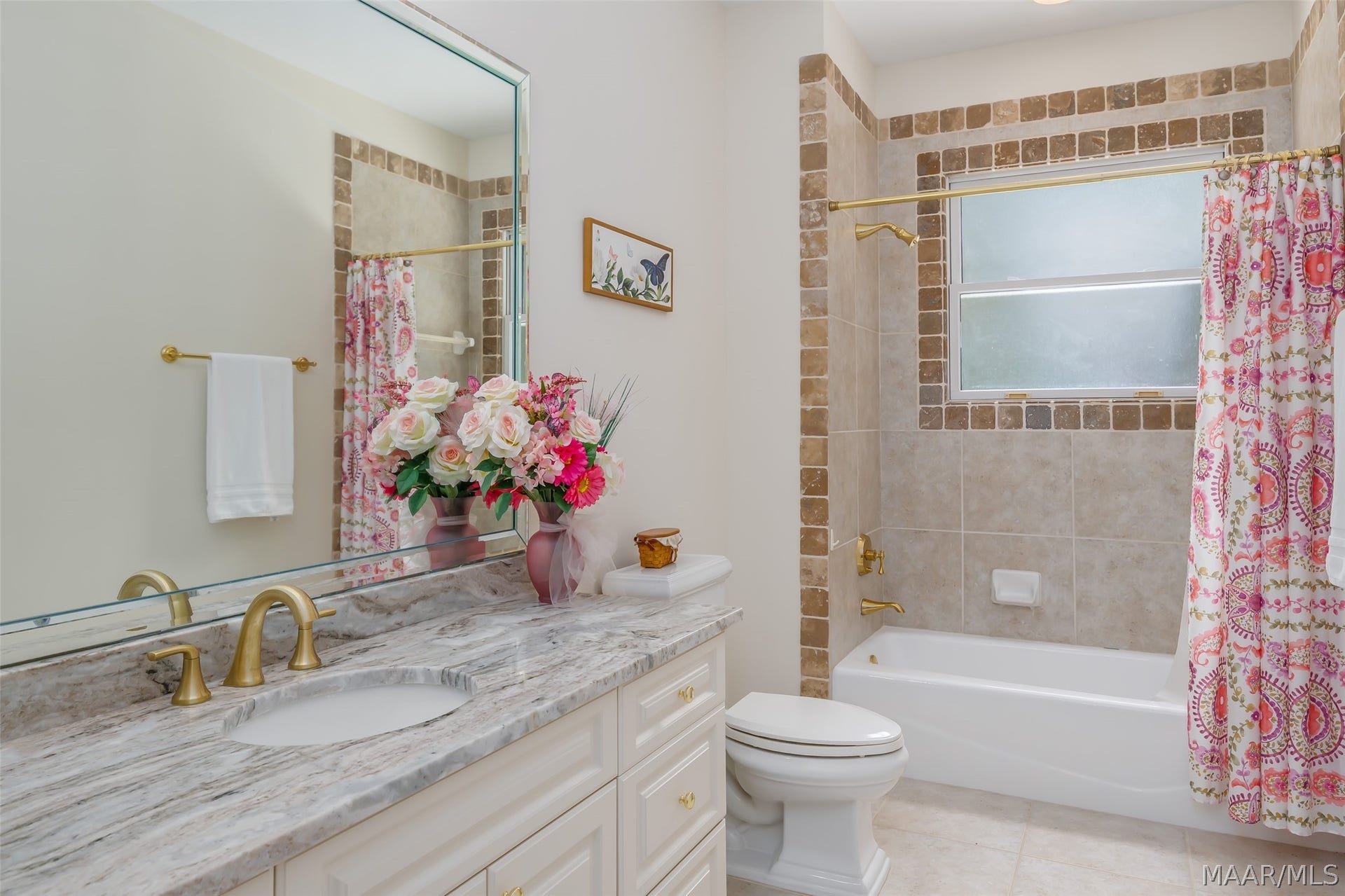 Well-appointed full bath with stone-topped vanity, tiled tub/shower surround and classic brass fixtures.