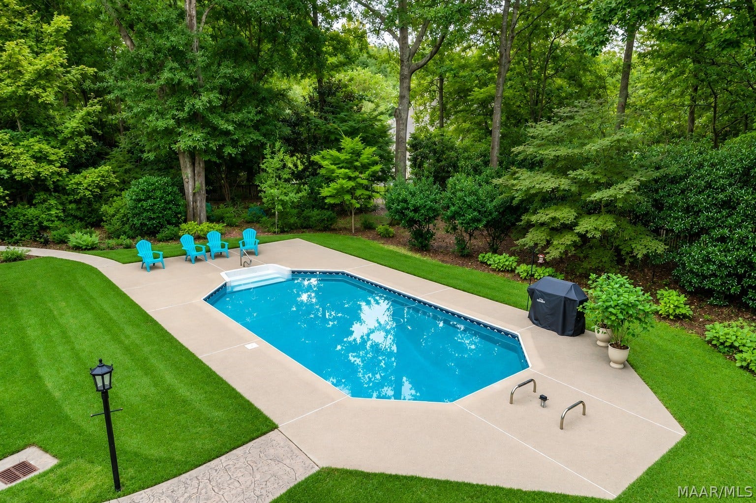 A sparkling pool surrounded by lush lawn and mature trees creates a serene, resort-like setting with exceptional privacy and natural beauty.