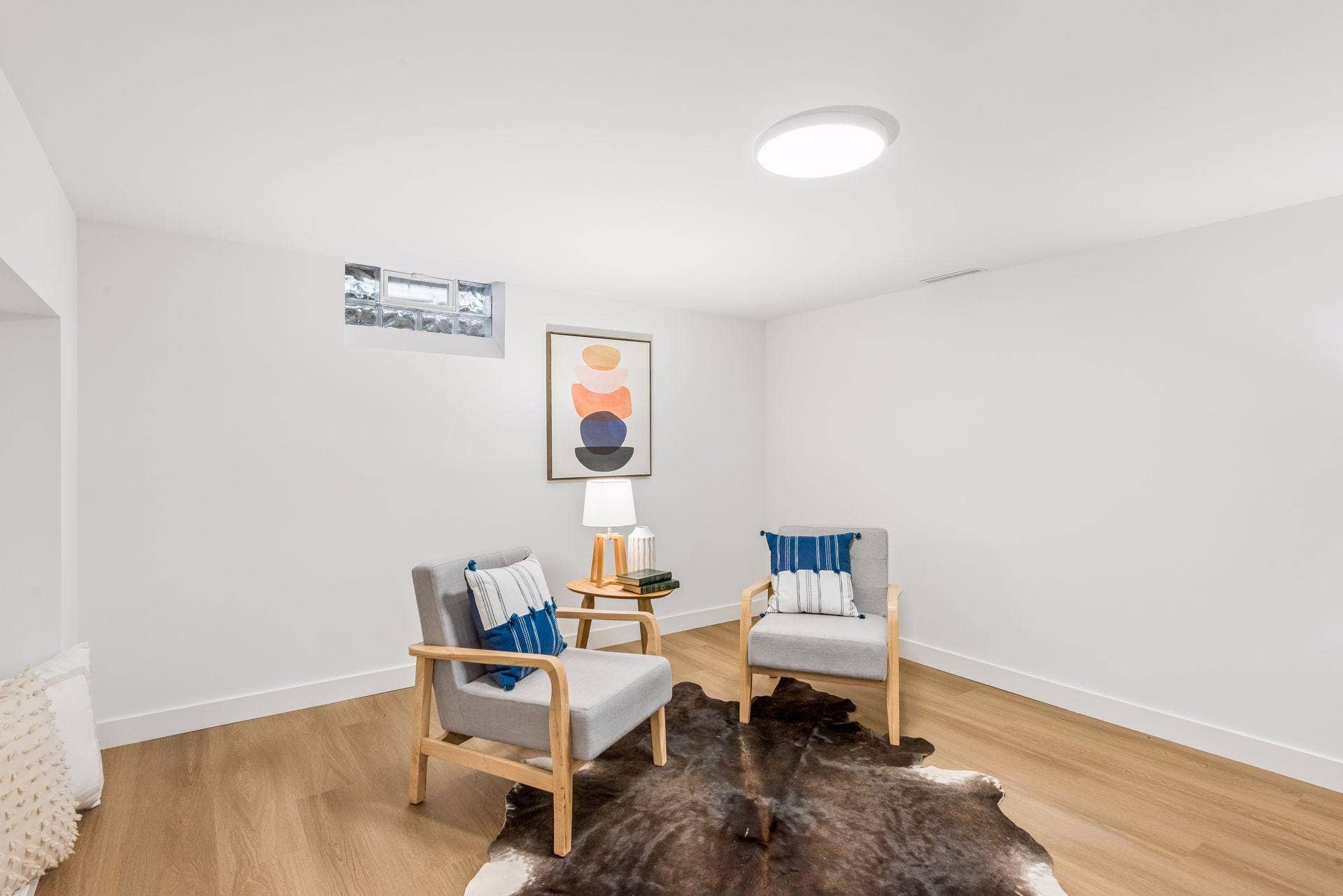 34x14 Lower level Family room with East-facing updated glass block windows, new paint, new luxury vinyl flooring, and lighting.