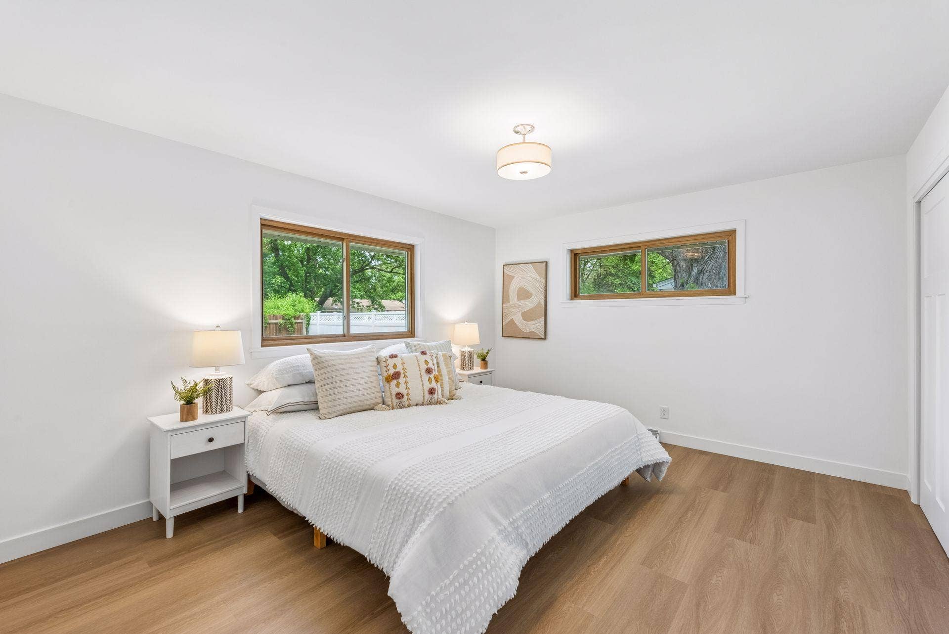 14x12 Main floor Bedroom #1 with East and north-facing updated windows, new paint, New trim and closet doors, new luxury vinyl flooring, and lighting.