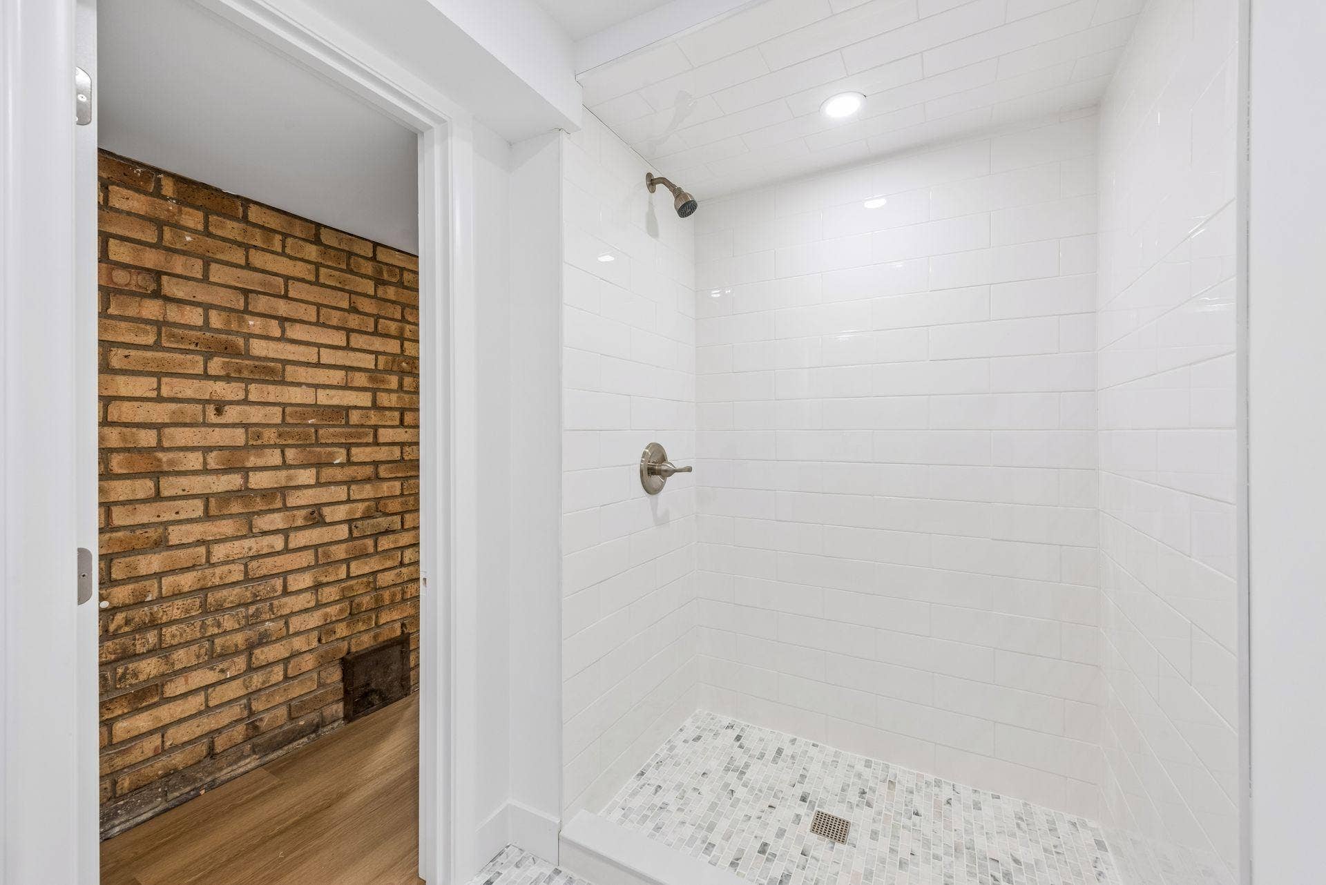 Lower Level 3/4 bathroom with updated Subway tile shower, White oak vanity with quartz top and Room and Board Mirror, New toilet, New lighting, and Marble flooring