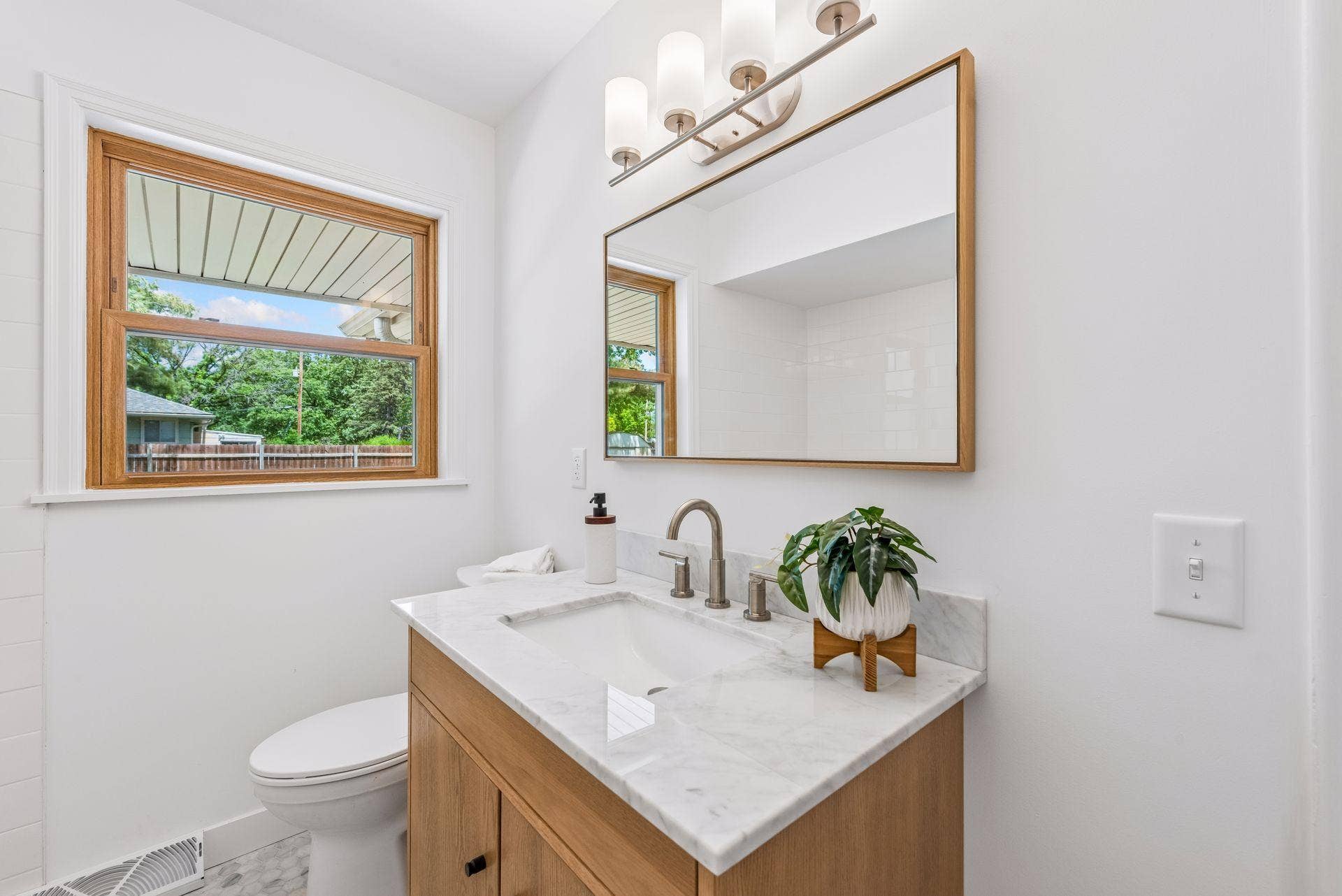Main Floor: Full bathroom with updated Subway tile, White oak Room and Board vanity with marble top and Mirror, New toilet, New lighting, and Marble flooring