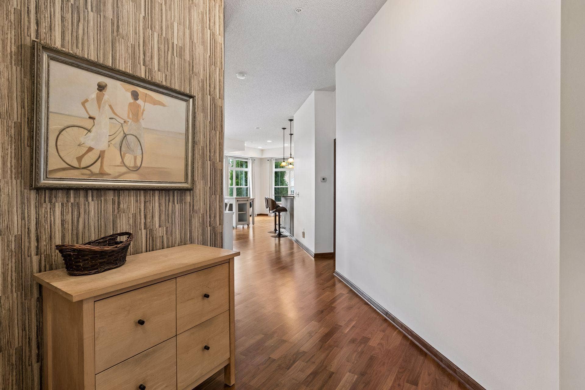 A spacious foyer introduces the home, leading into an open-concept living environment where soaring ceilings, expansive windows, and warm wood flooring create a bright and cohesive atmosphere.