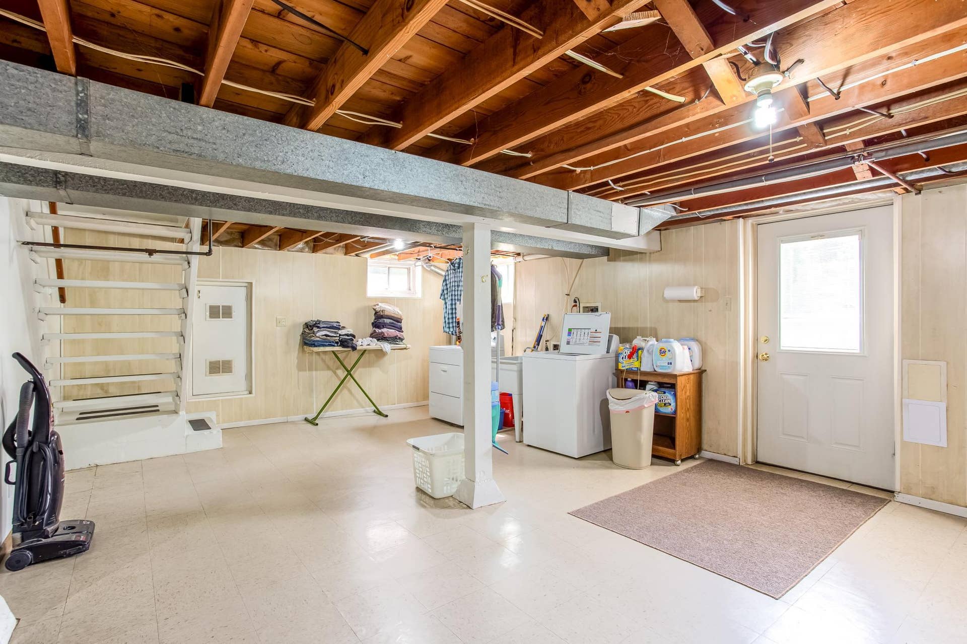 Spacious partially finished lower level offers a dedicated laundry area, convenient exterior access, and plenty of room for additional household needs.