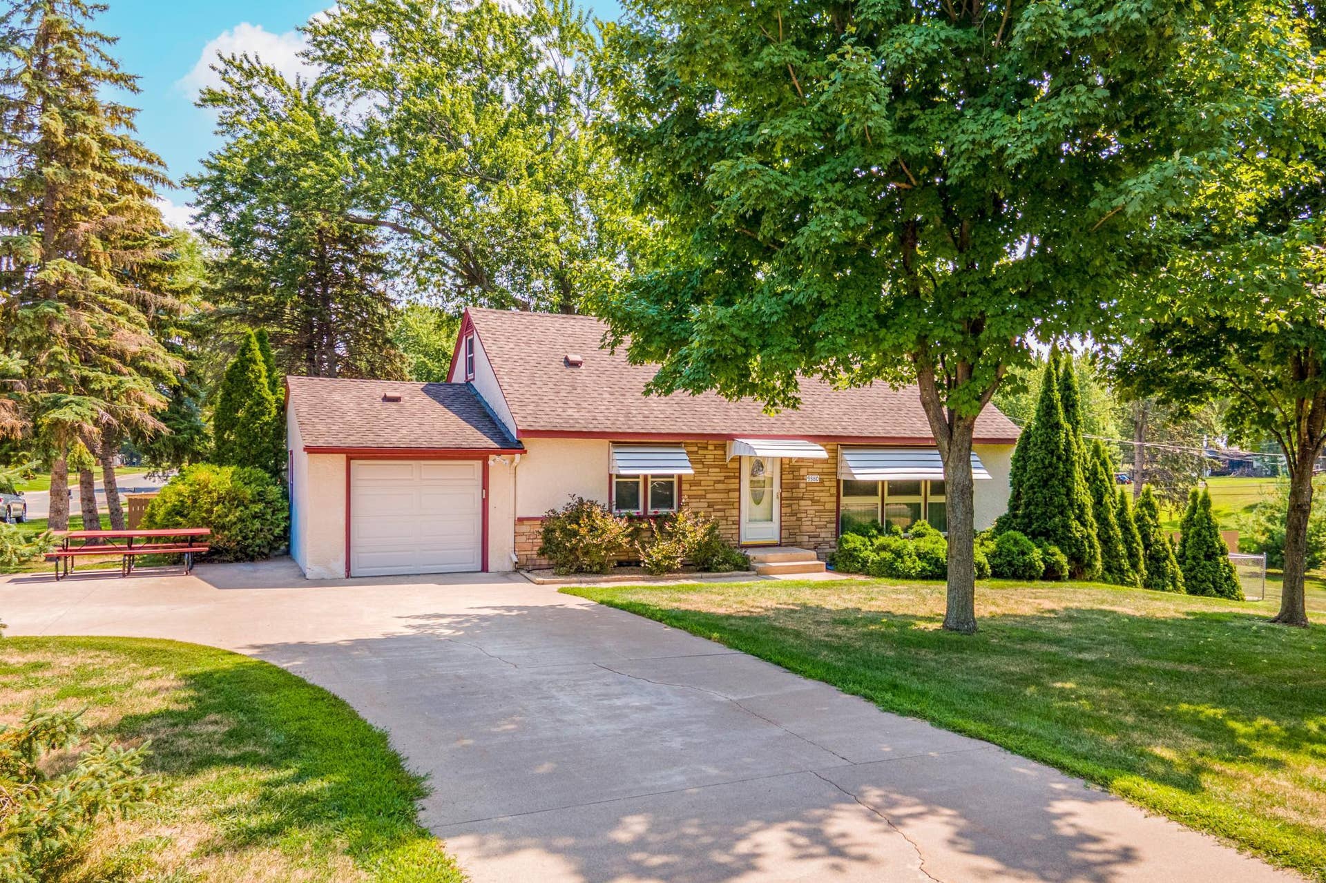 Gorgeous curb appeal welcomes you home, with mature trees, established landscaping, and an attached garage creating an inviting first impression.