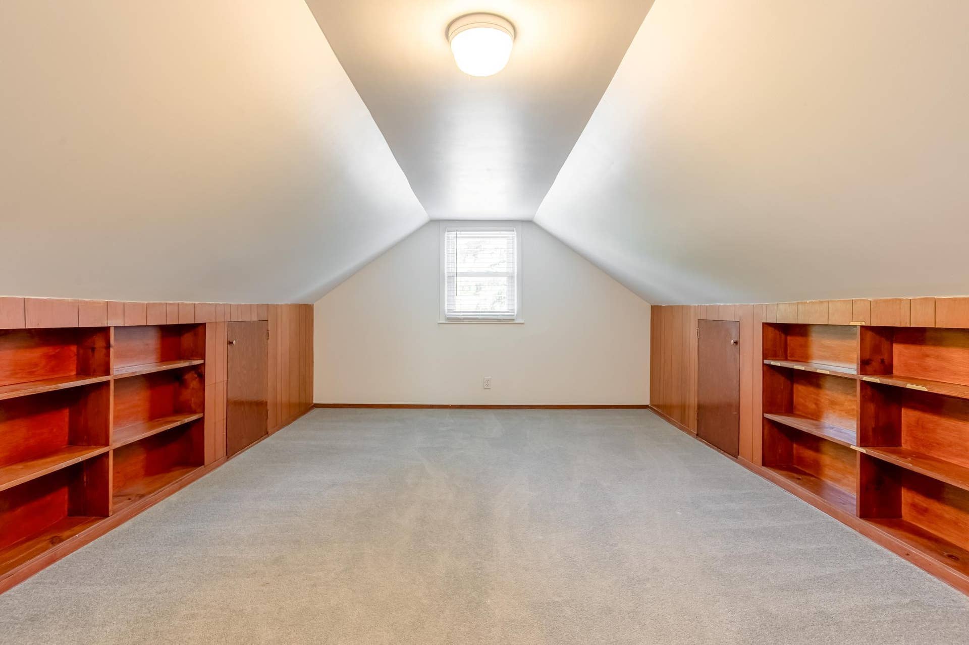 Versatile upper-level bedroom features a charming sloped ceiling, built-in shelving, and convenient integrated storage.