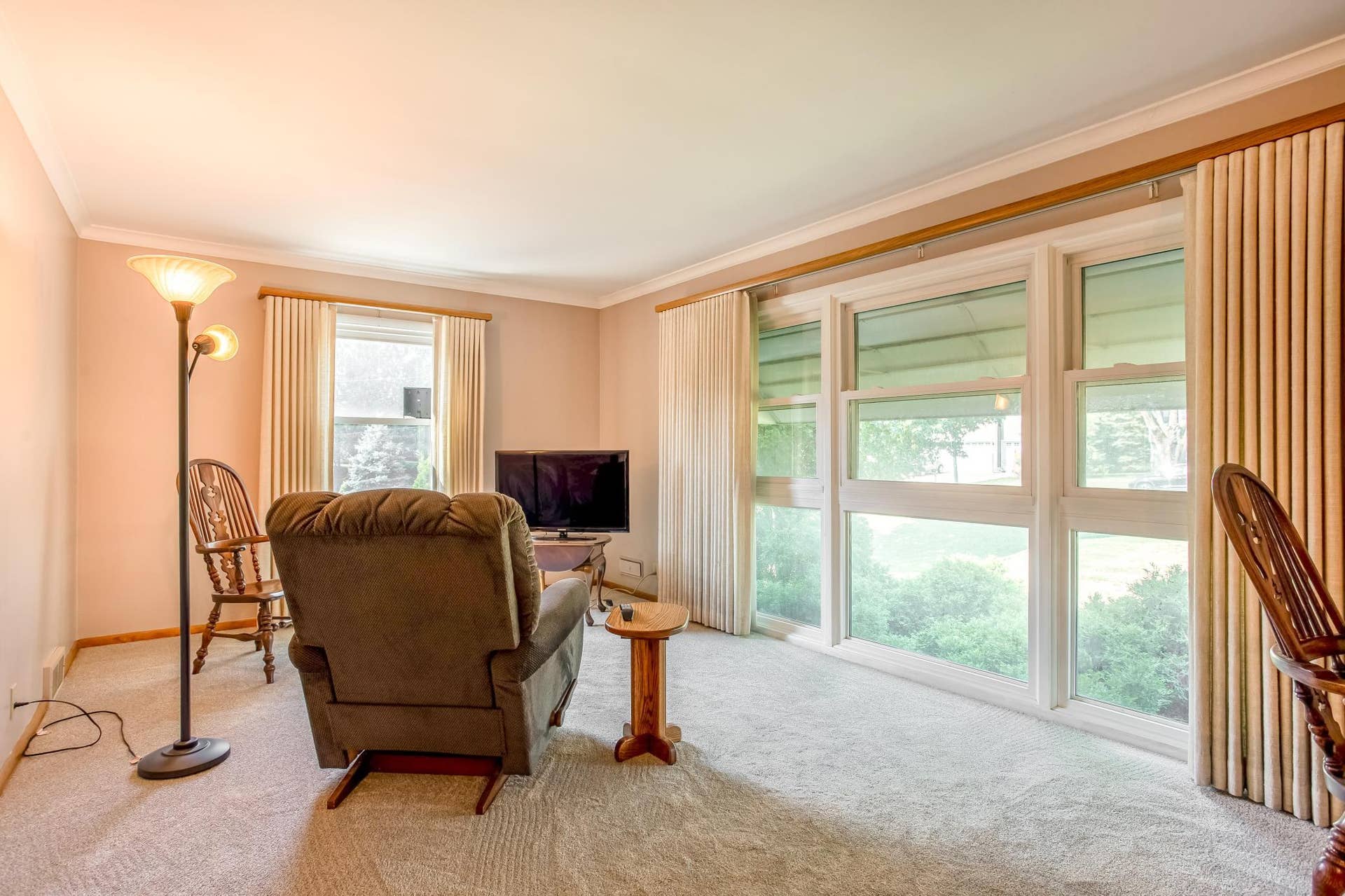 Bright and inviting living room with an impressive floor-to-ceiling wall of windows offering abundant natural light and pleasant views of the surrounding greenery.